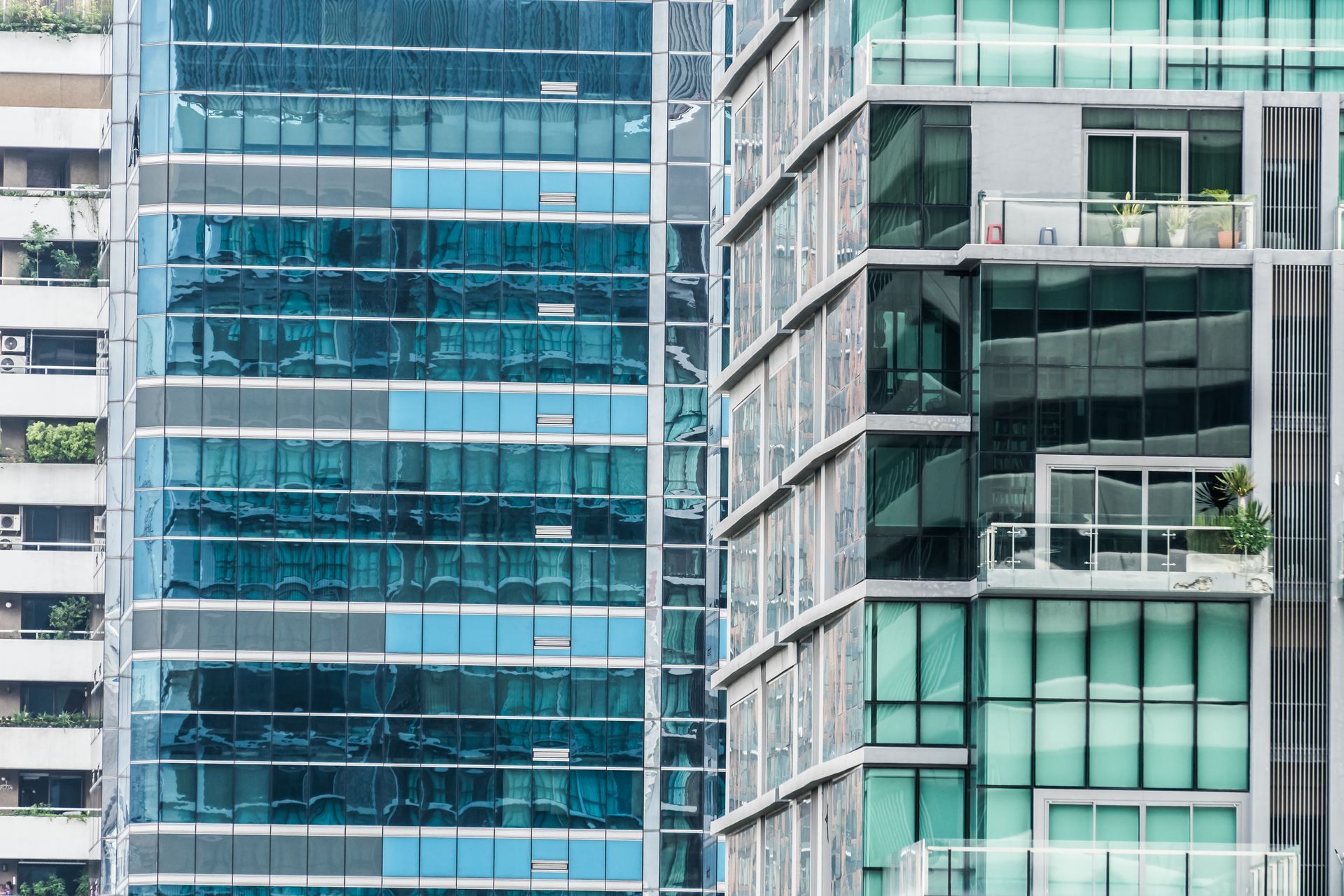 Edificios modernos de gran altura con fachadas de vidrio reflectante azul, balcones y motivos arquitectónicos geométricos.