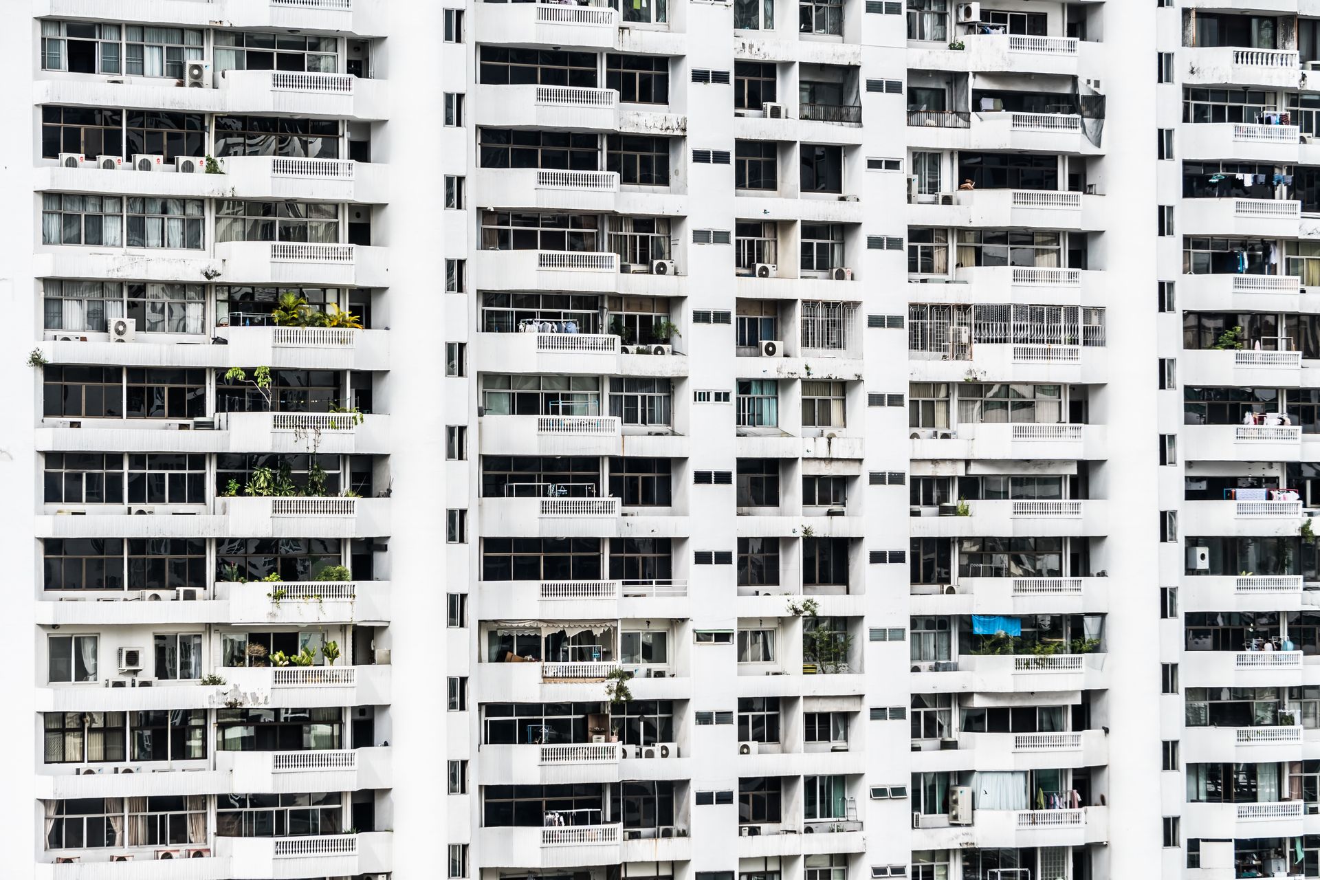 Un edificio de apartamentos alto y blanco con balcones y ventanas que se repiten