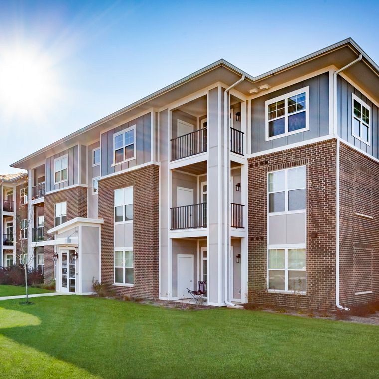 A large apartment building with a lot of windows and balconies at Flats at Stones Crossing.