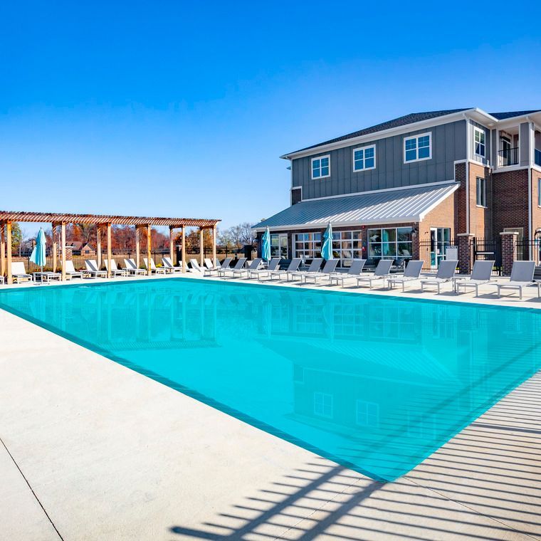 A large swimming pool in front of a large house at Flats at Stones Crossing.