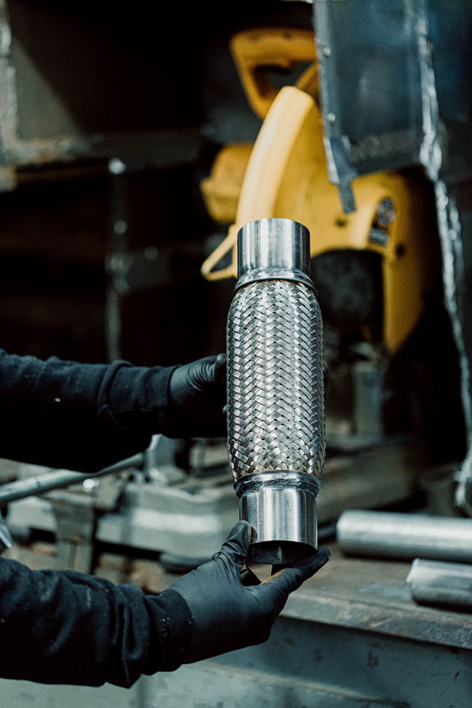 A person is holding a stainless steel exhaust pipe in their hands.