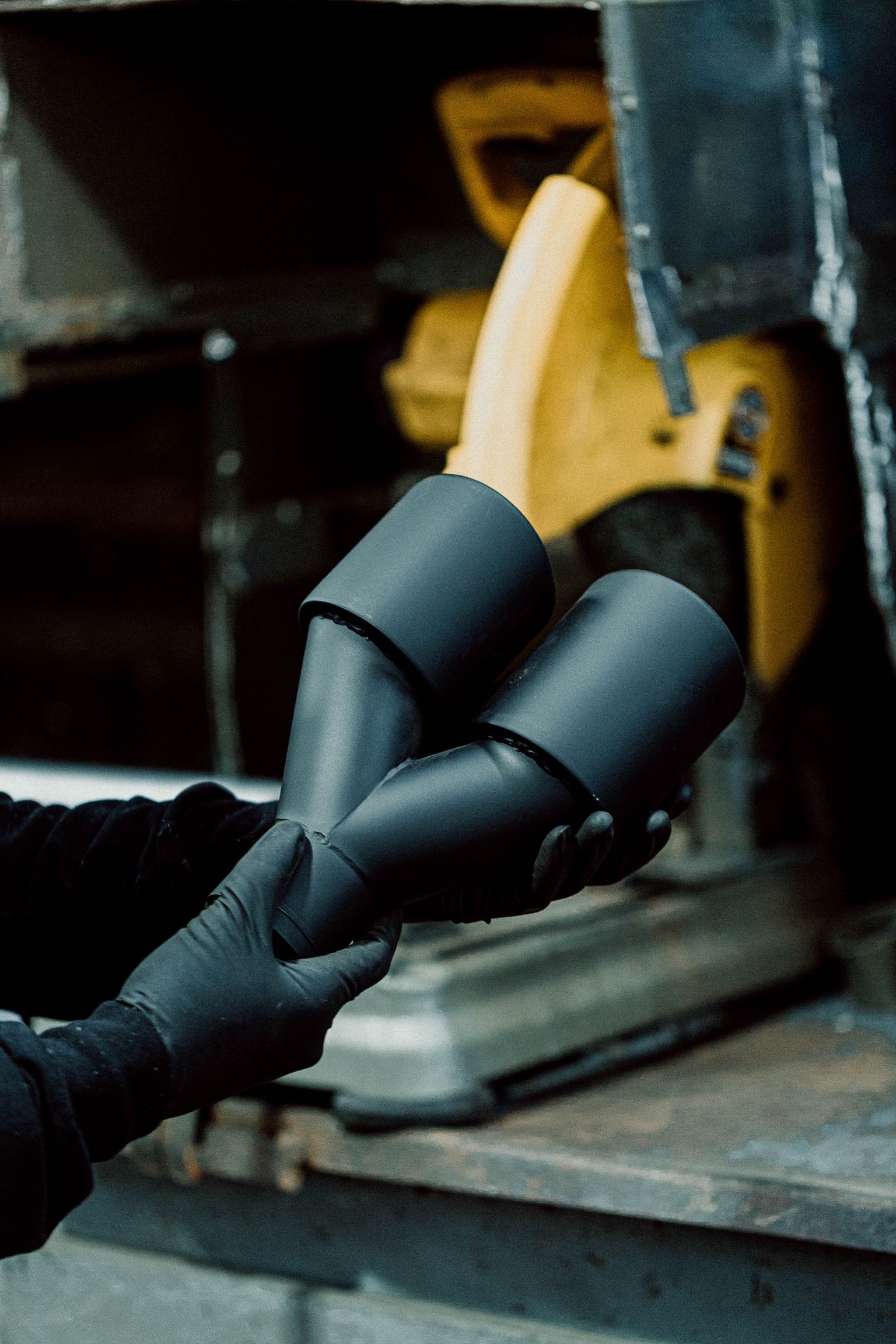 A person wearing black gloves is holding a piece of metal.