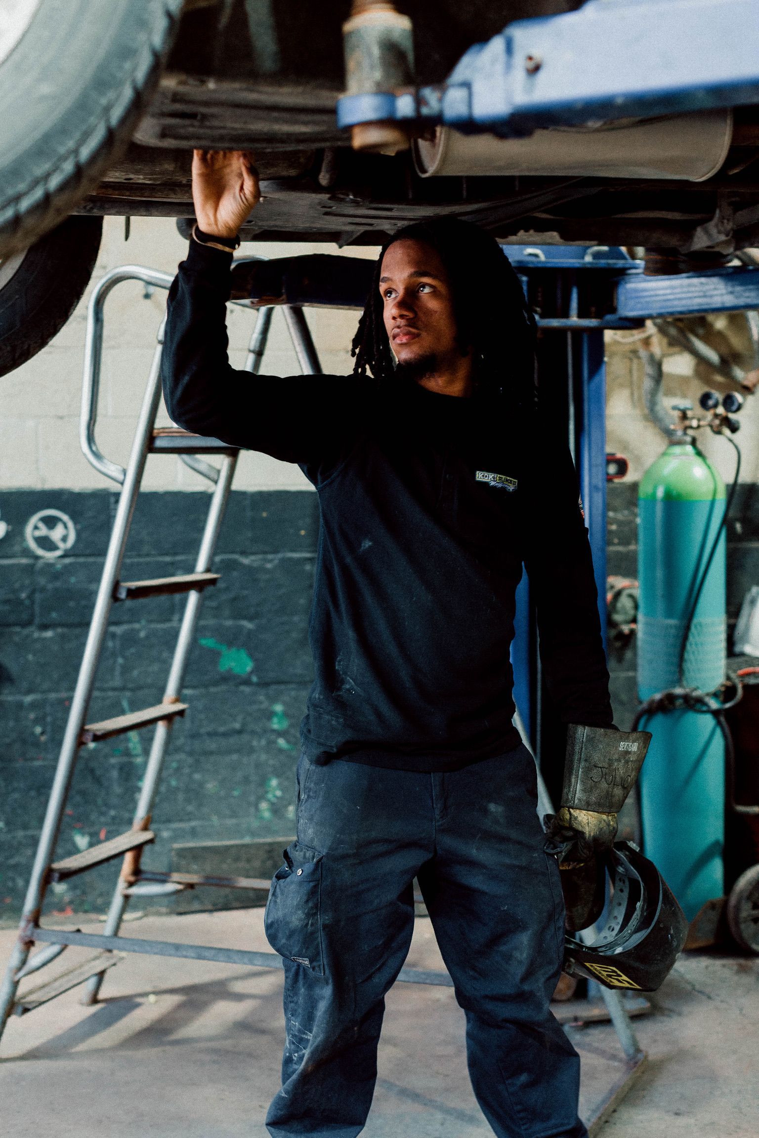 A man is working under a car in a garage.