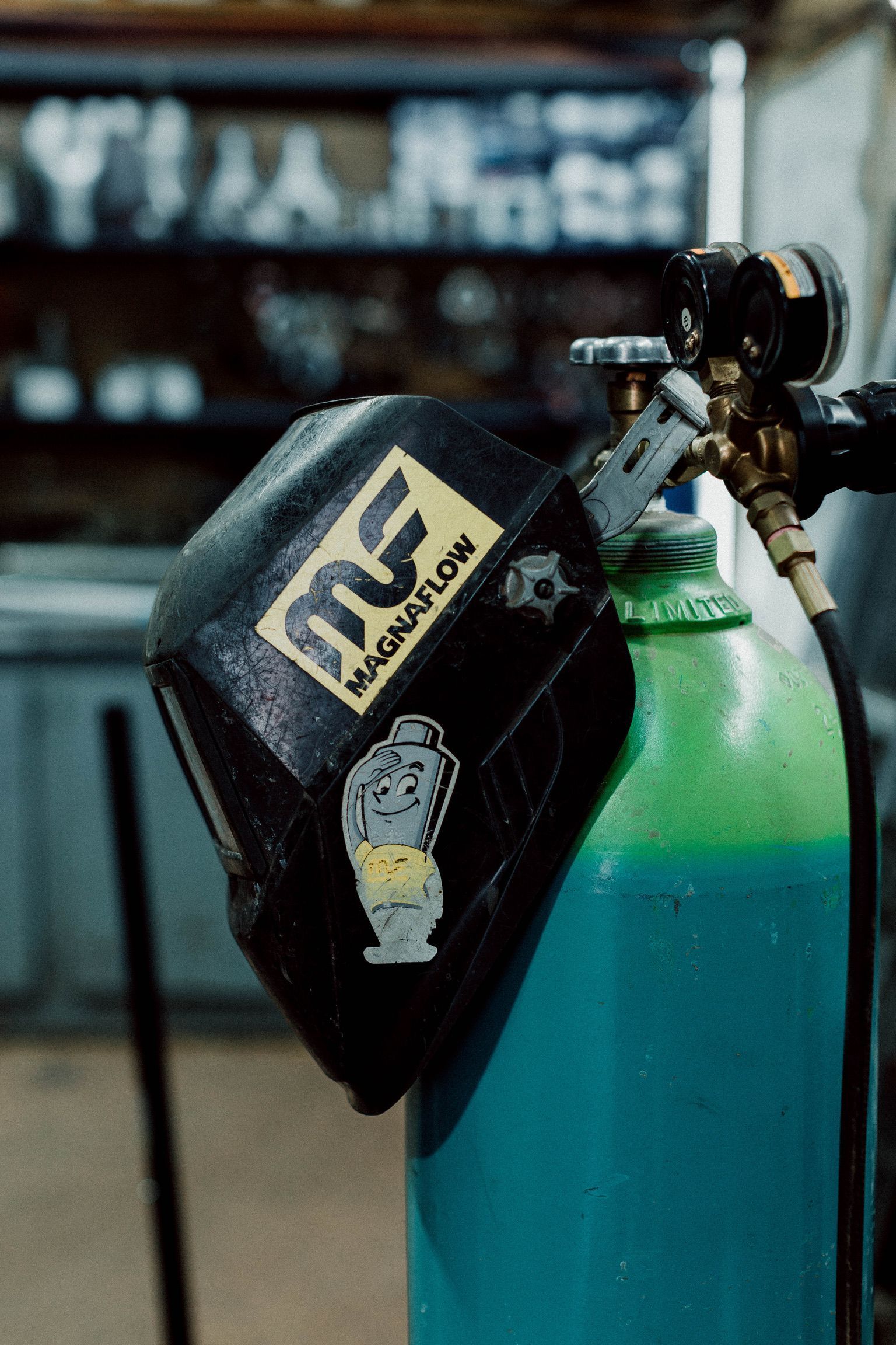 A welding helmet is sitting on top of a gas cylinder.