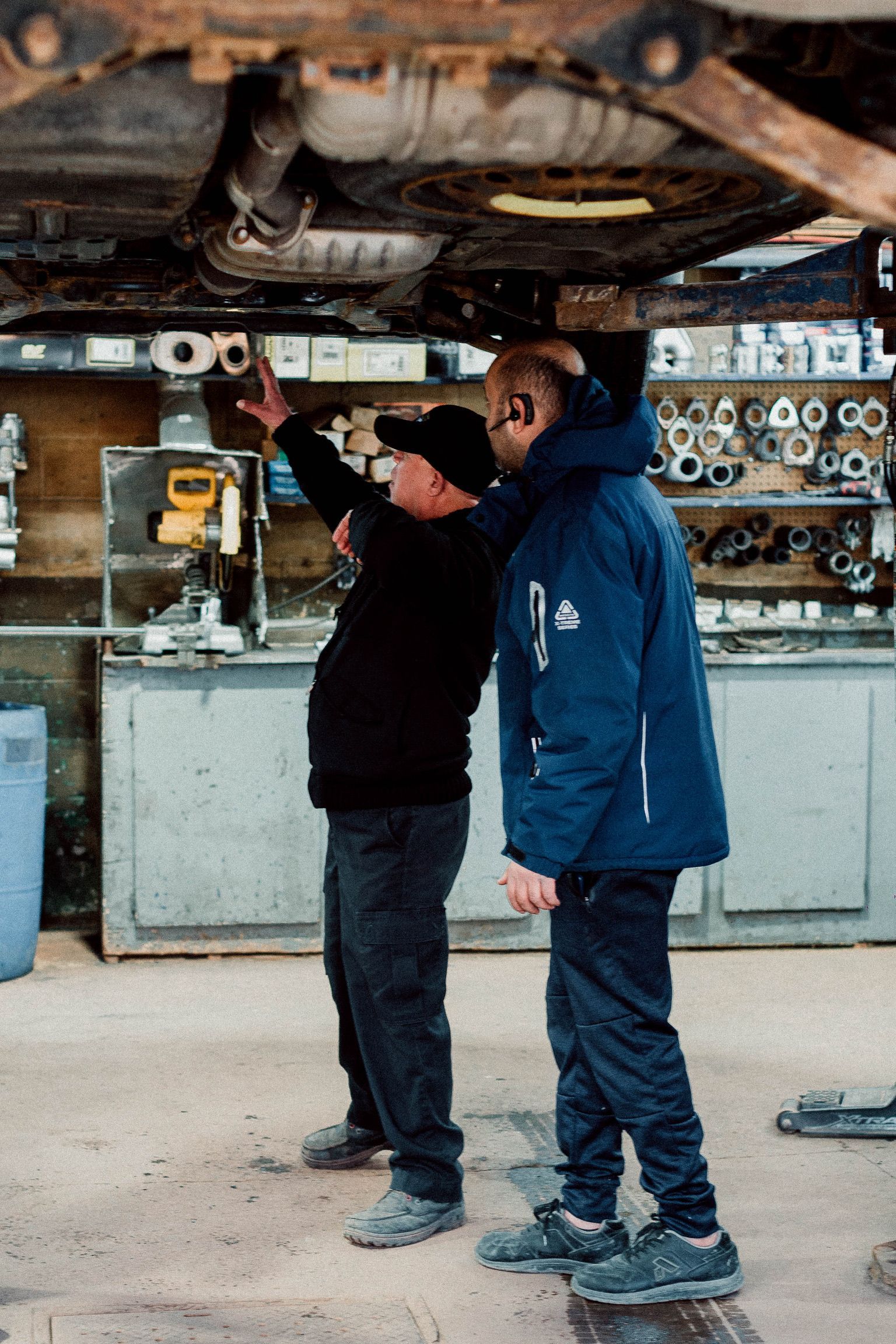 Two men are working under a car in a garage