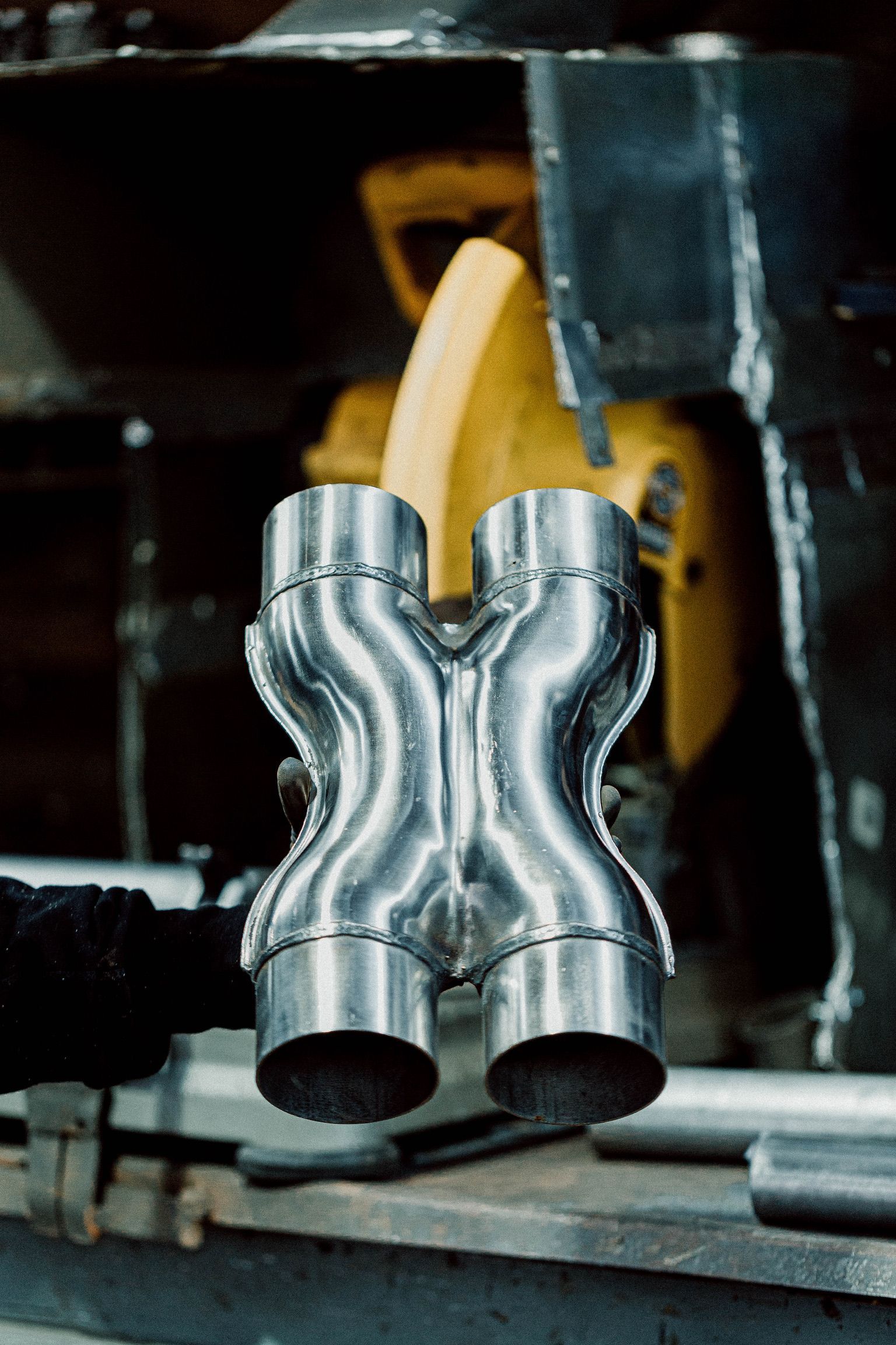 A metal pipe is sitting on a table next to a yellow tool.