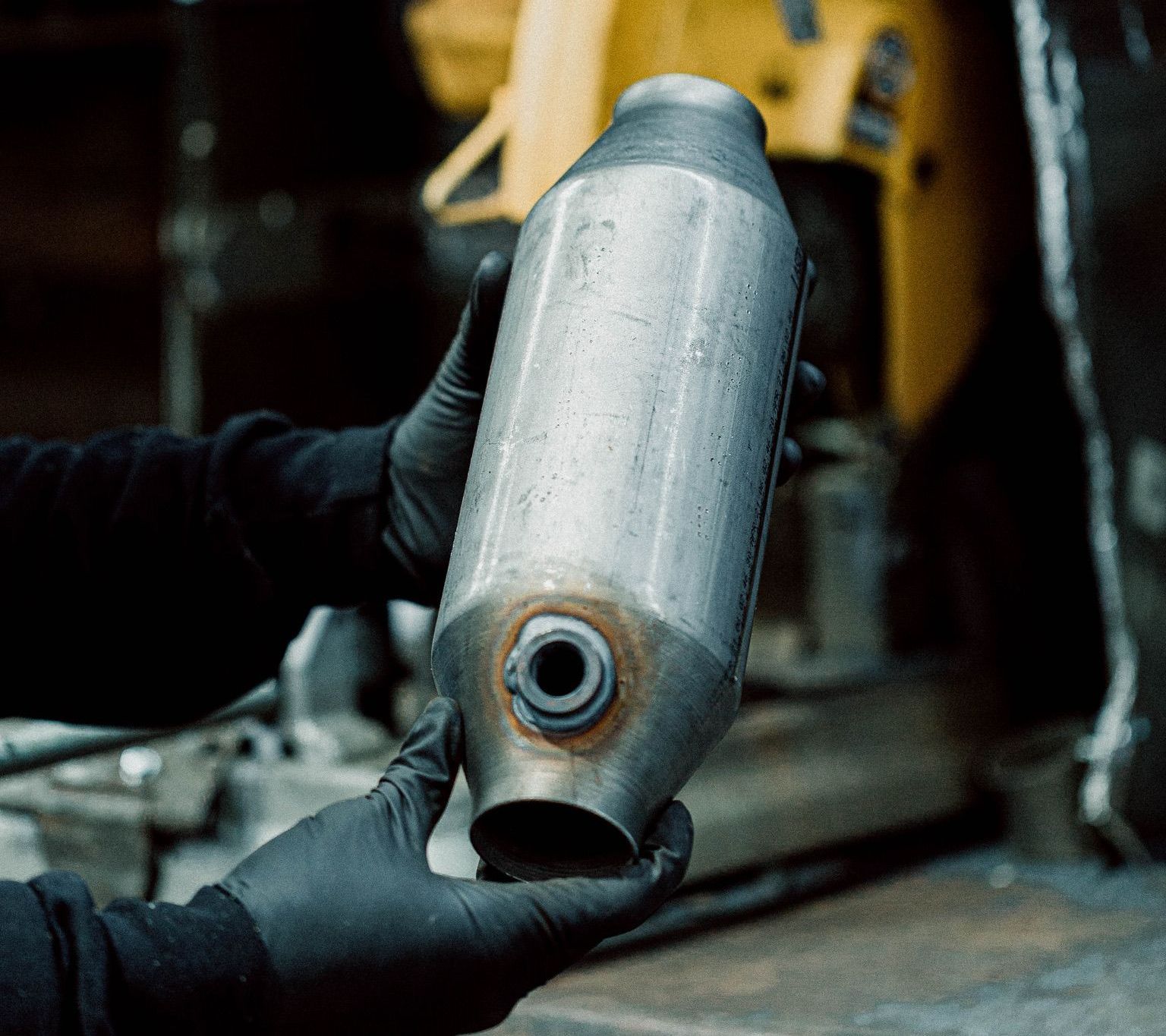 Une personne portant des gants noirs tient un objet métallique dans sa main.