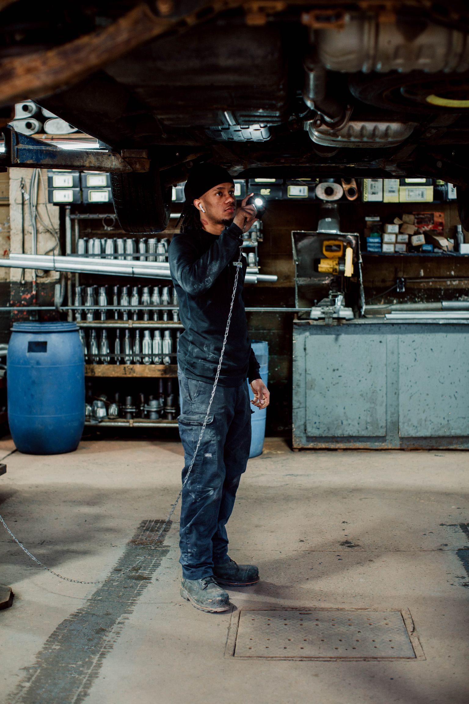 A man is standing in a garage holding a hose.