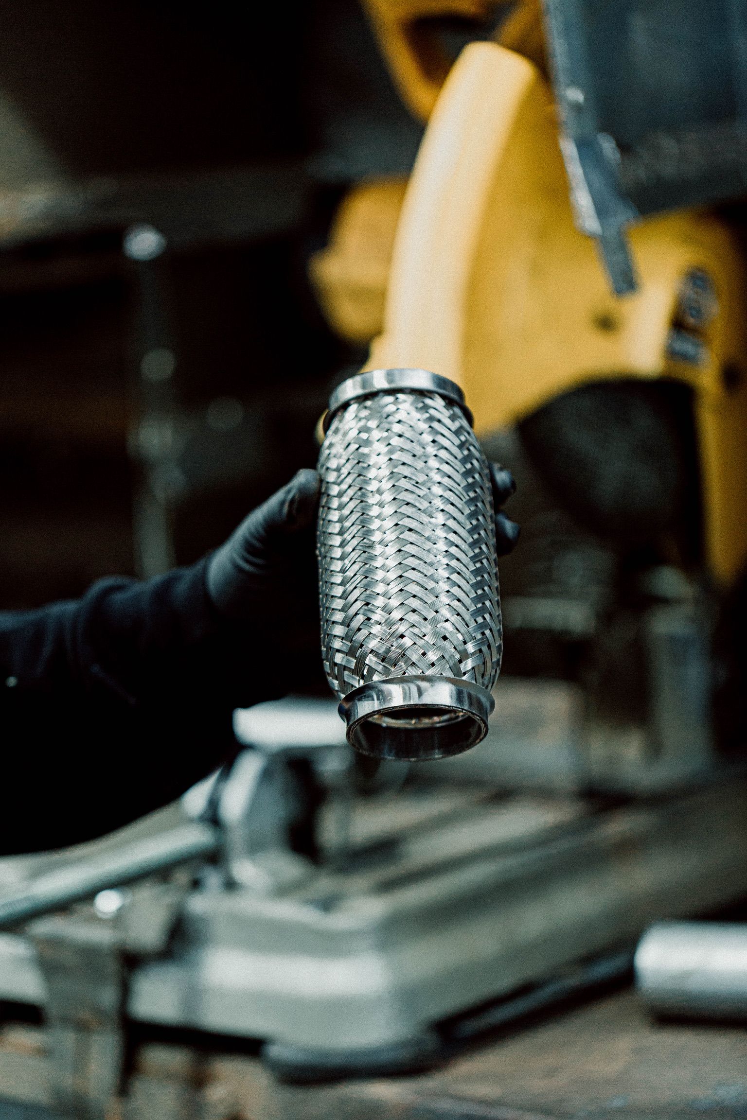 A person is holding a metal pipe in their hand in front of a circular saw.