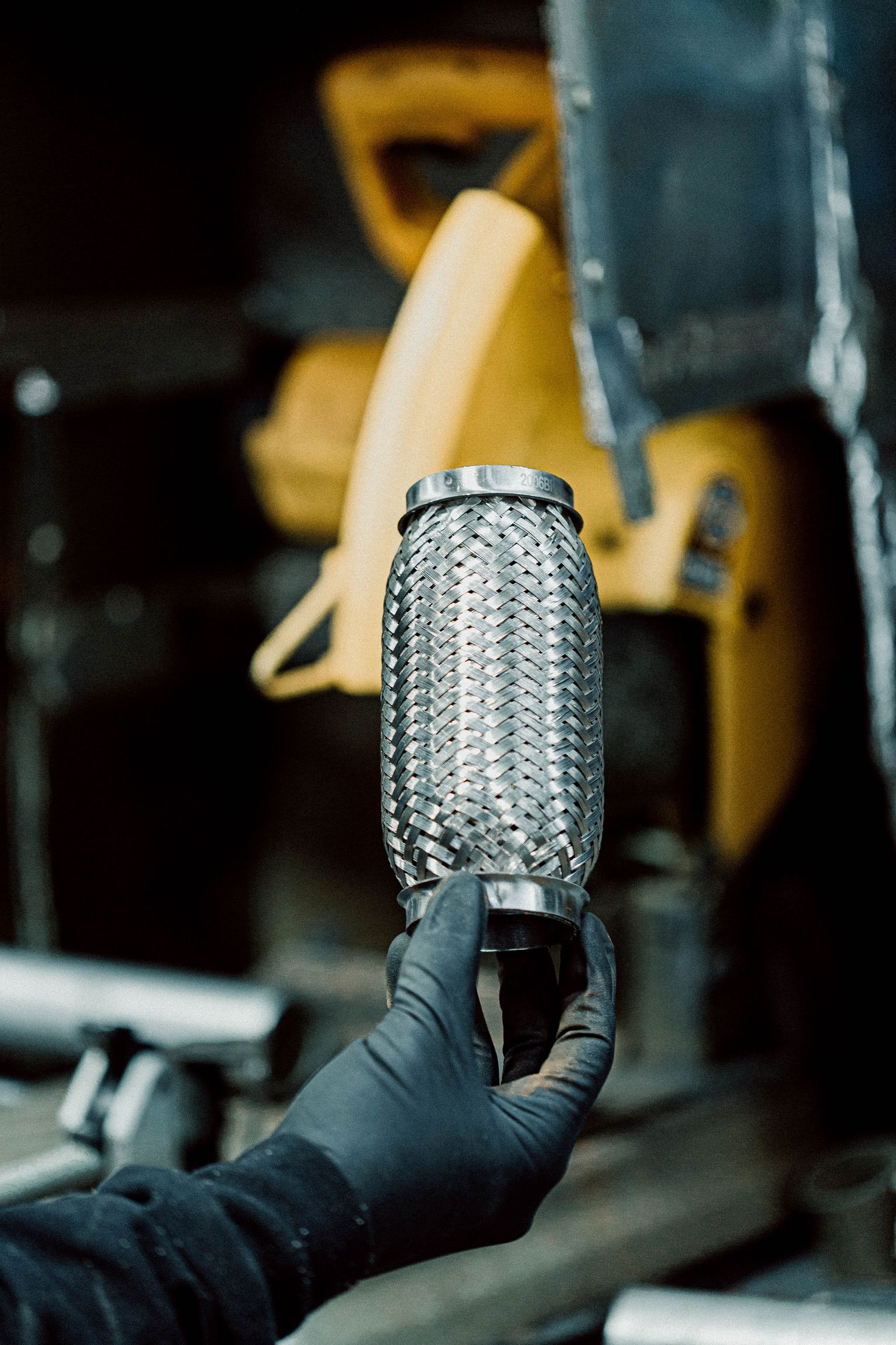 A person wearing black gloves is holding a metal pipe in their hand.
