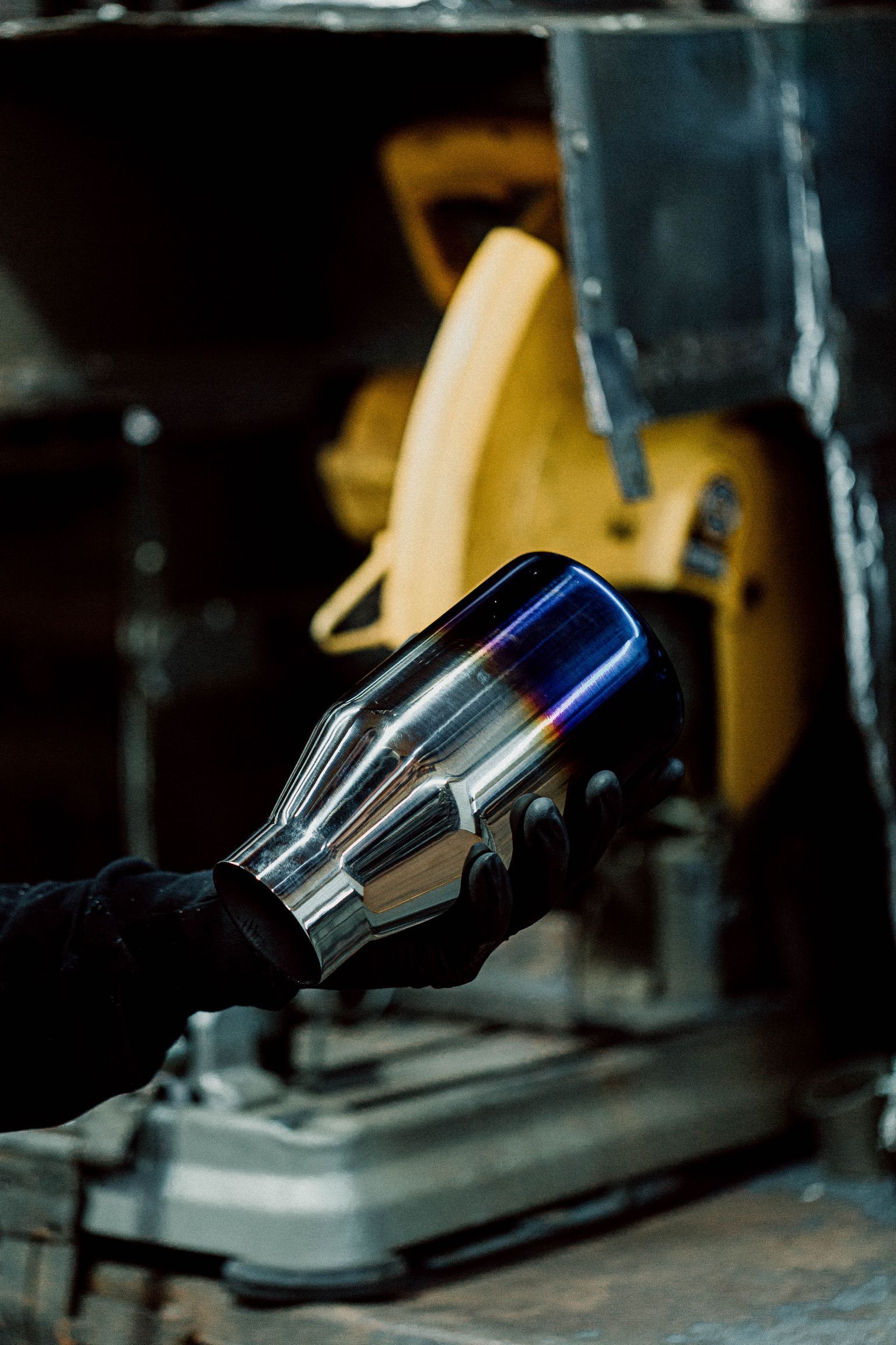 A person is holding a exhaust pipe in front of a circular saw.