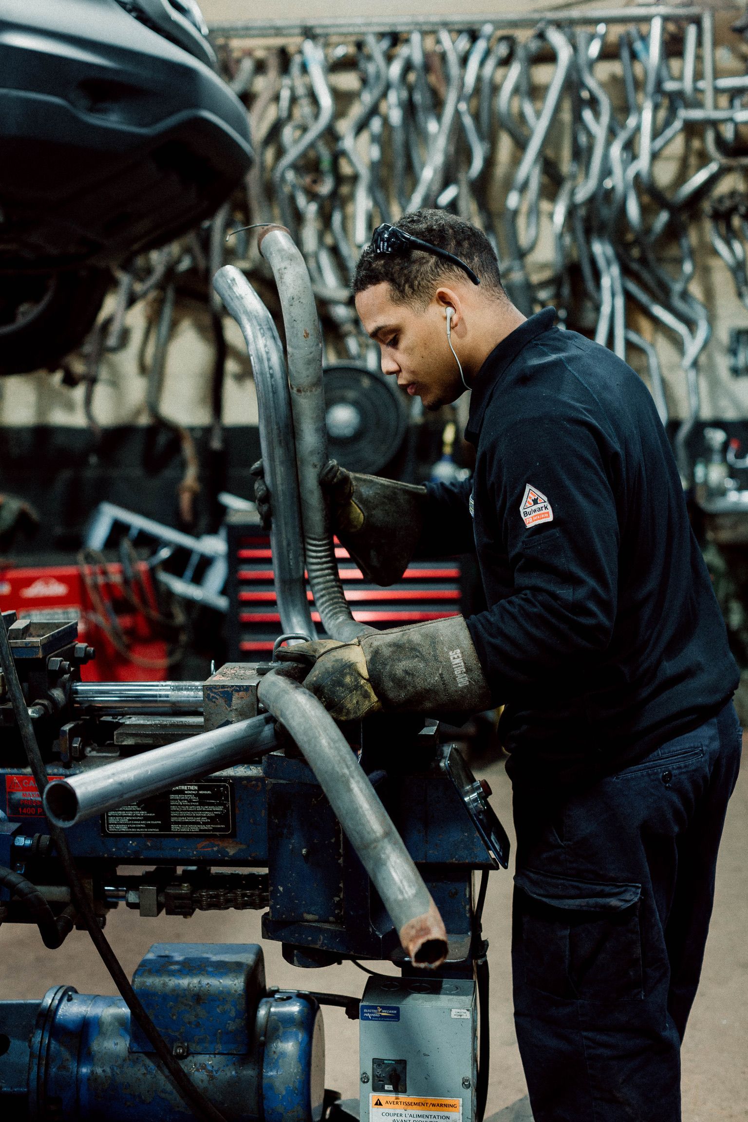 A man is working on a pipe in a garage.