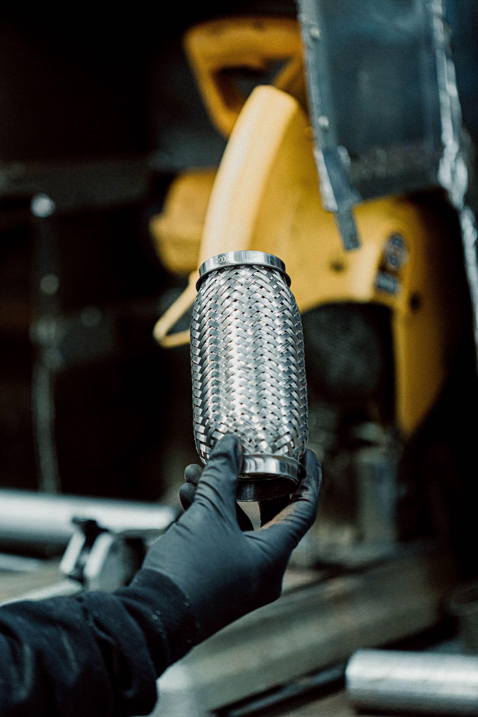 A person wearing black gloves is holding a metal pipe in their hand.