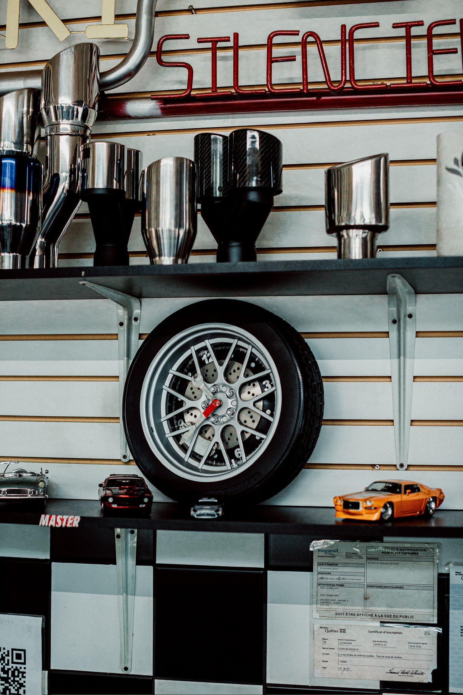 A clock hanging on a wall next to a tire