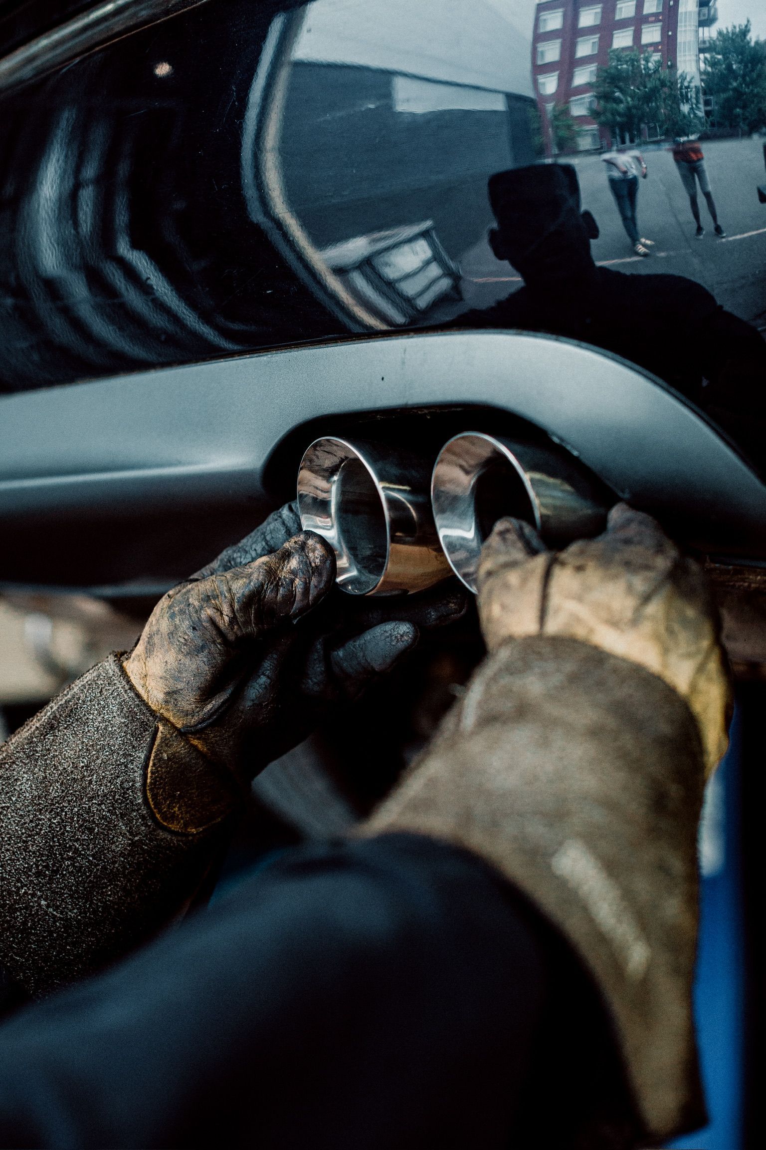 A person is working on the exhaust pipe of a car.