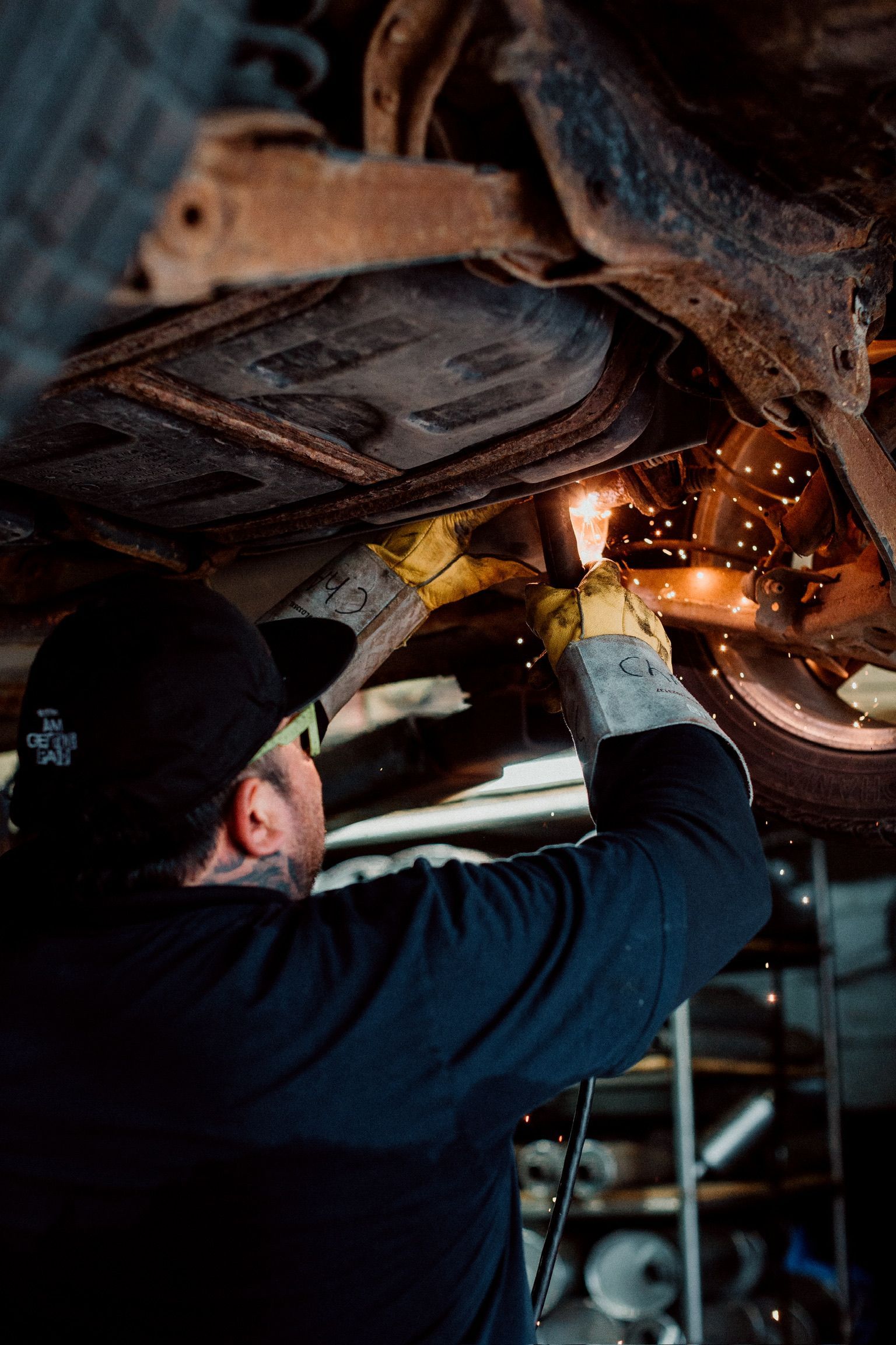 A man is working under a car in a garage.