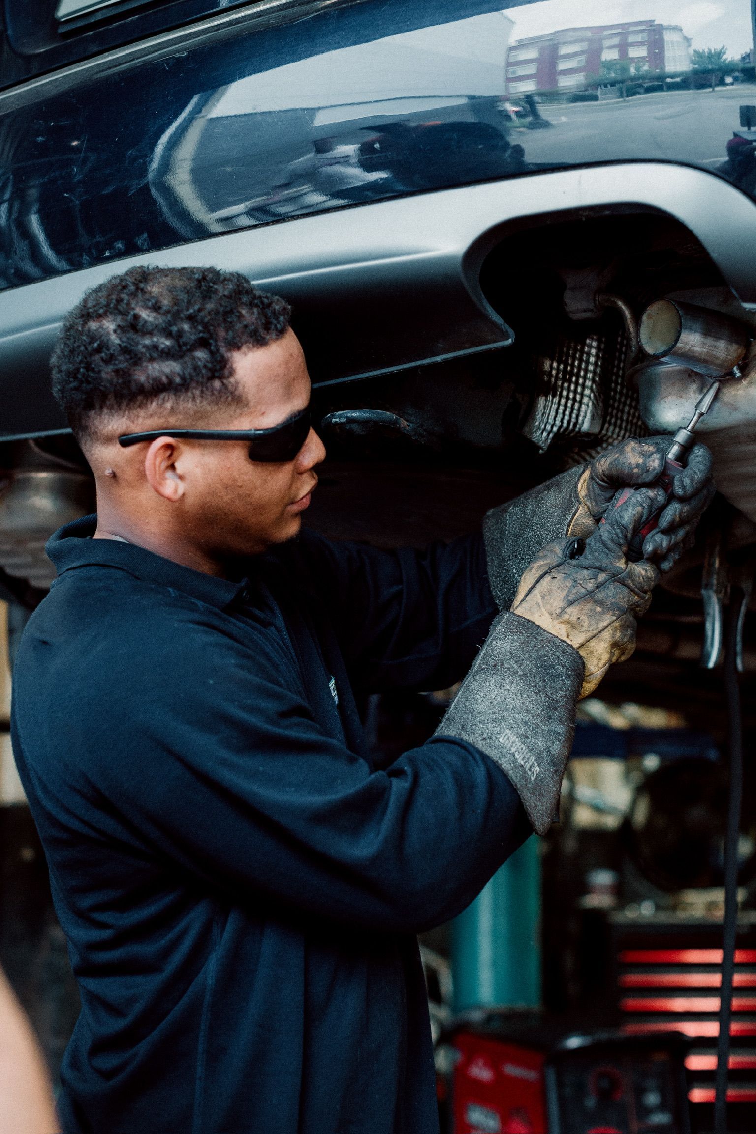 A man is working on the exhaust pipe of a car.