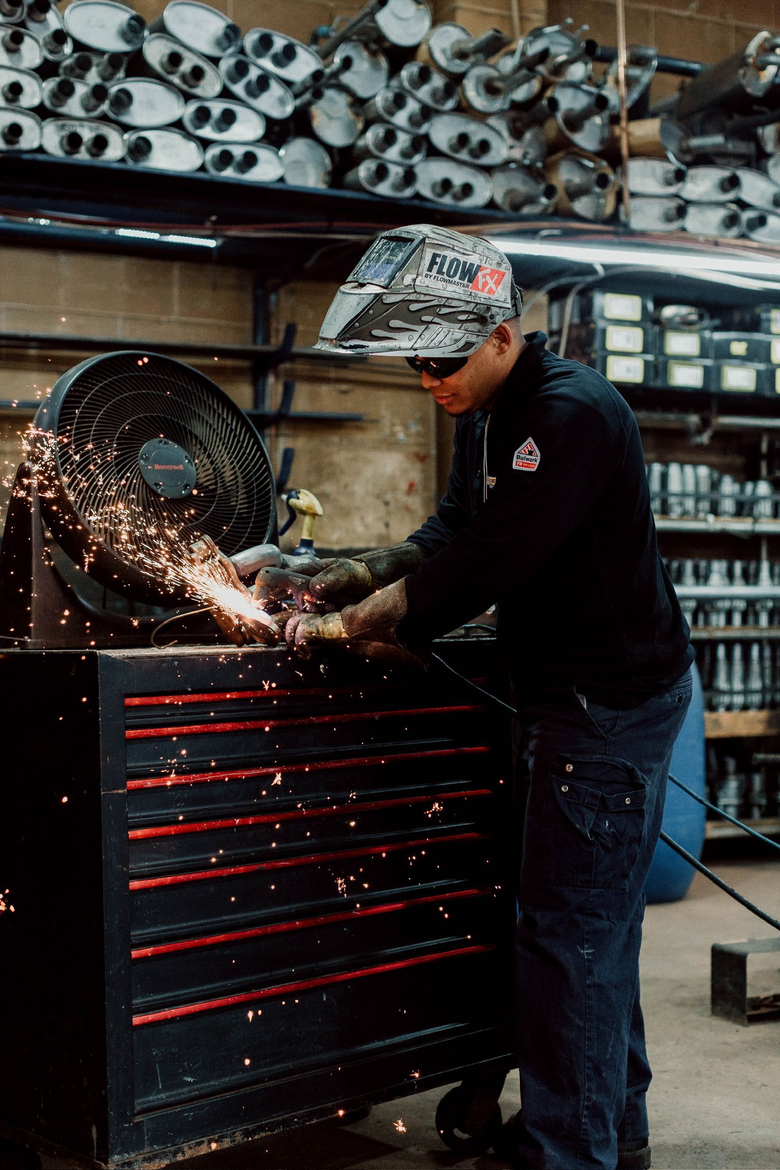 A man wearing a welding helmet is working on a piece of metal.