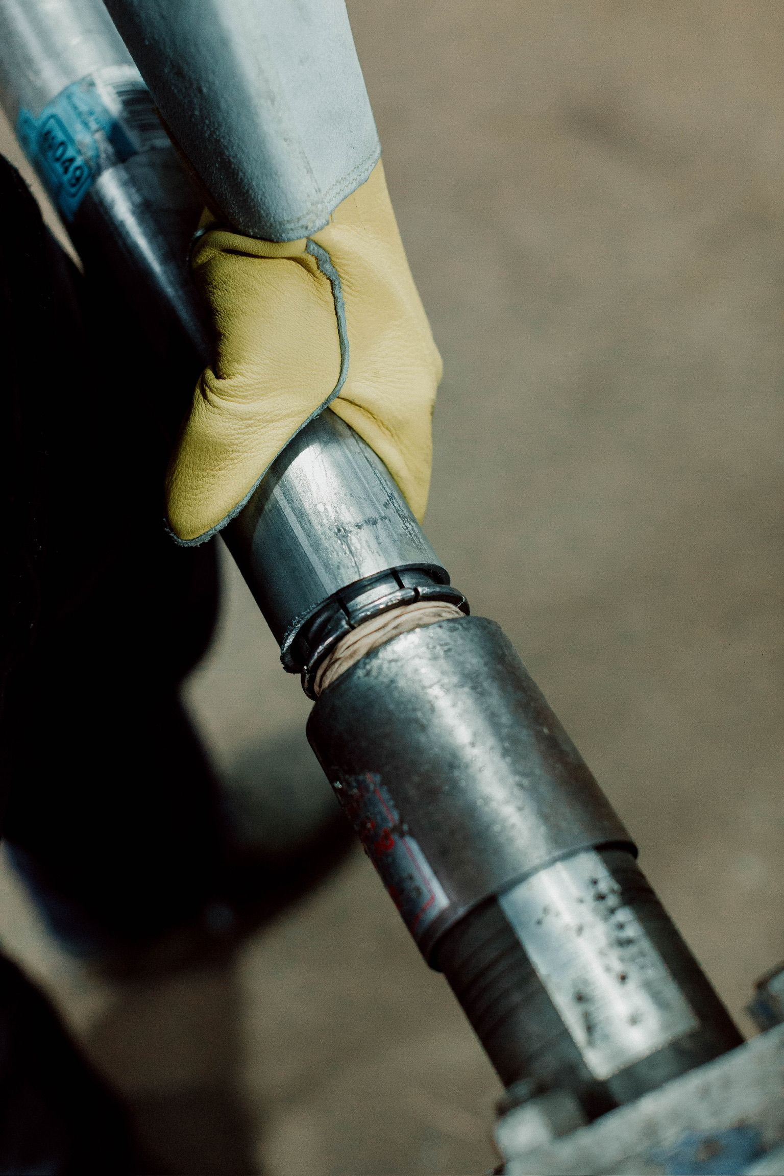 A person wearing a yellow glove is holding a metal pipe