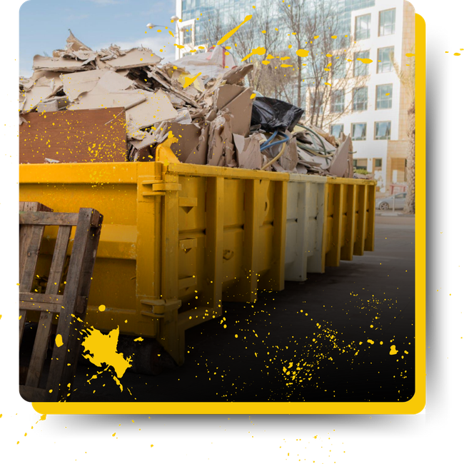 A yellow dumpster filled with cardboard is sitting on the side of the road.