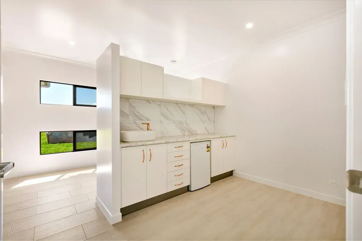 A Kitchen With White Cabinets, a Sink, and a Refrigerator — Ashlee Jones Homes in Tablelands, QLD