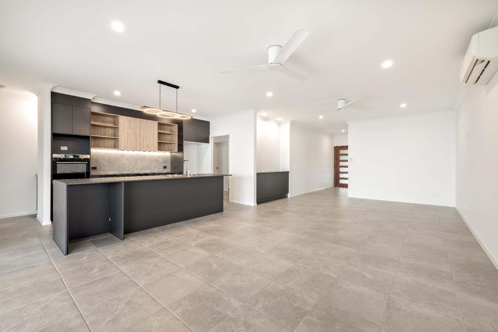A Large Empty Room With a Kitchen and a Ceiling Fan — Ashlee Jones Homes in Gordonvale, QLD