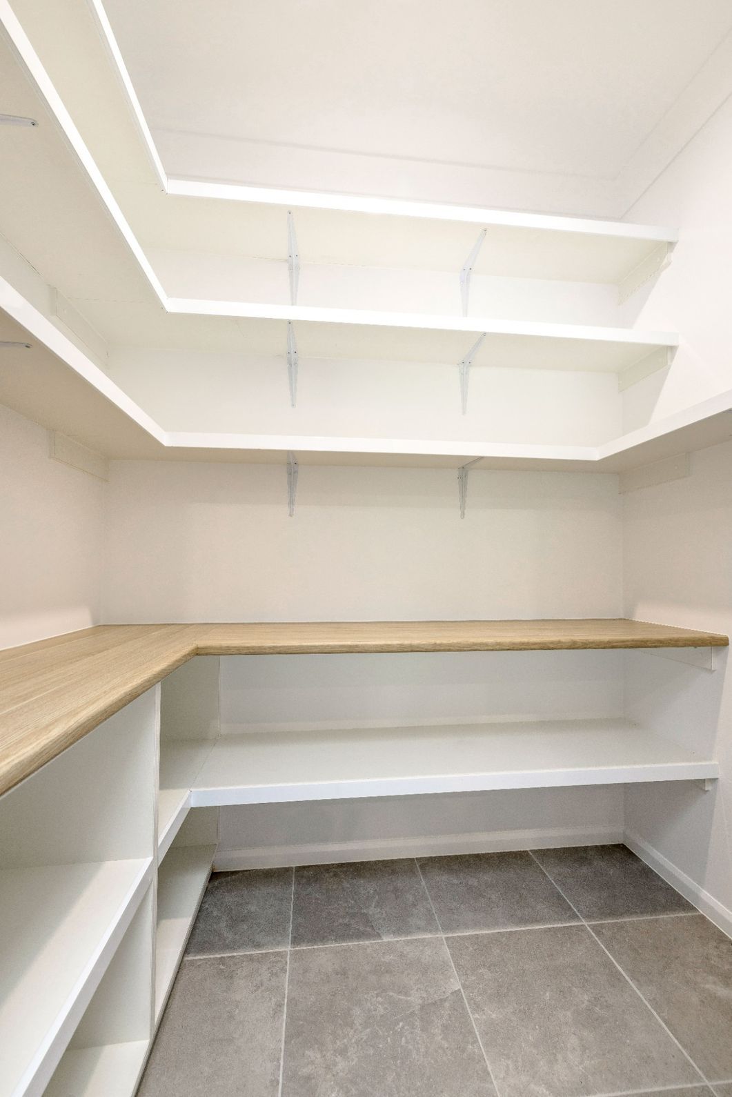 An Empty Walk in Pantry With White Shelves and Wooden Counter Tops — Ashlee Jones Homes in Gordonvale, QLD