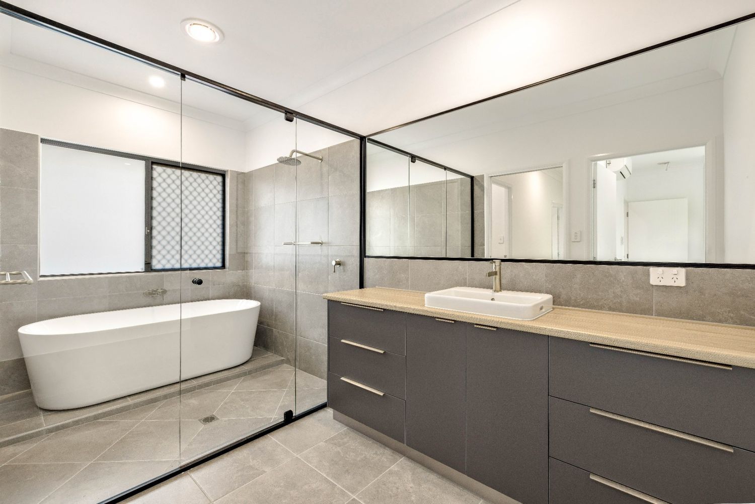 A Bathroom With a Bathtub, Sink and Mirror — Ashlee Jones Homes in Gordonvale, QLD