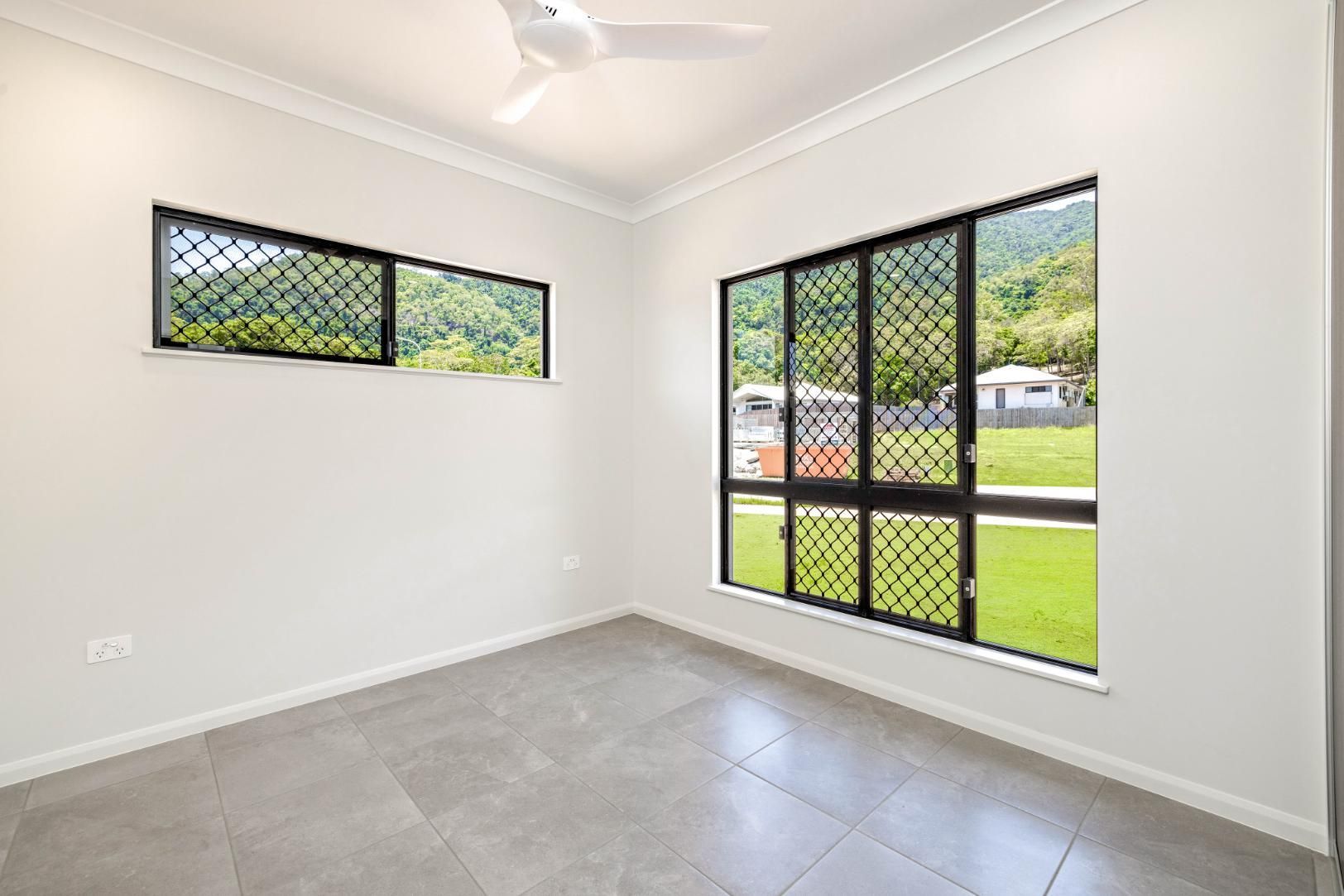 An Empty Room With Two Windows and a Ceiling Fan — Ashlee Jones Homes in Gordonvale, QLD