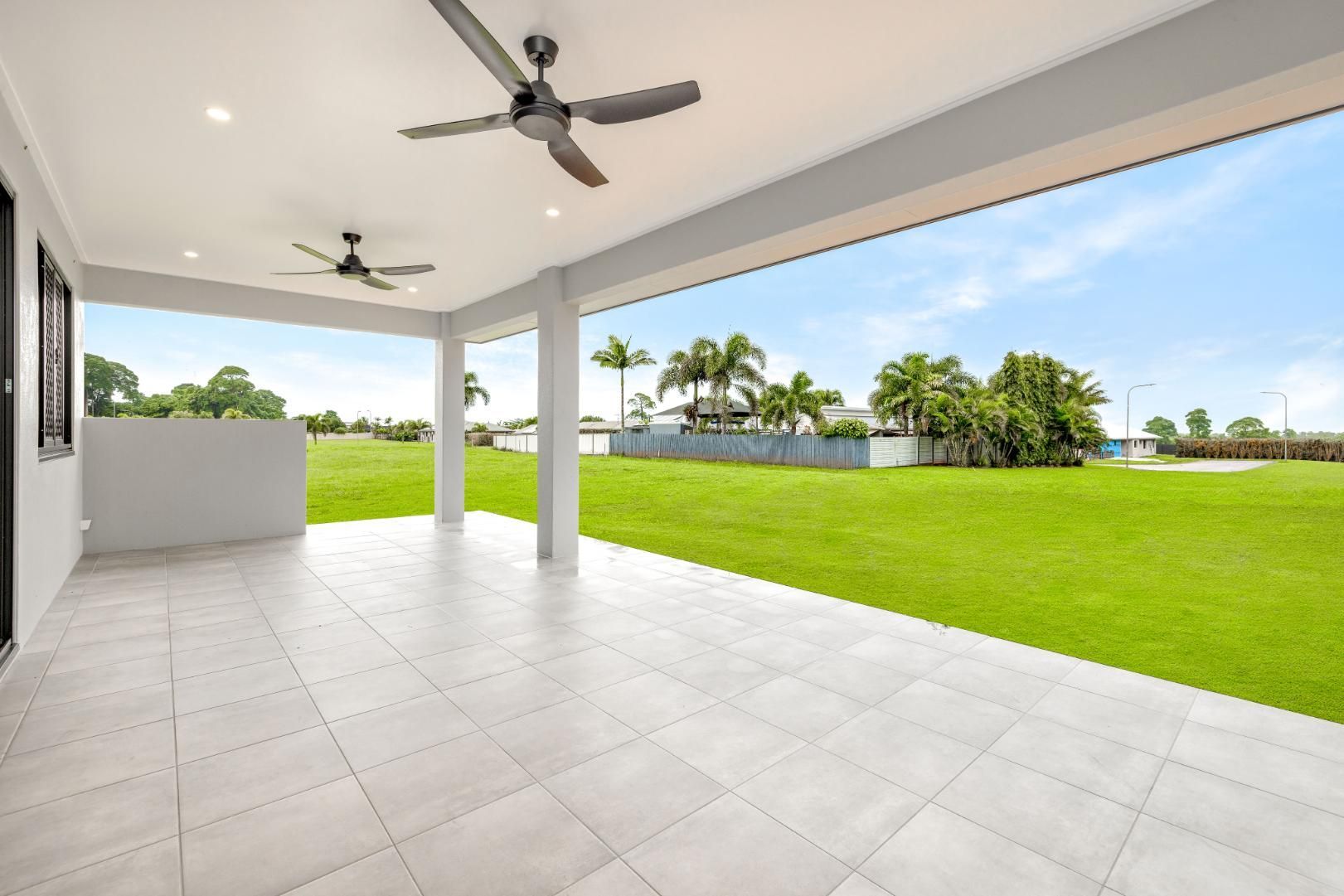 An Empty Patio With a Ceiling Fan and a View of a Grassy Field — Ashlee Jones Homes in Gordonvale, QLD