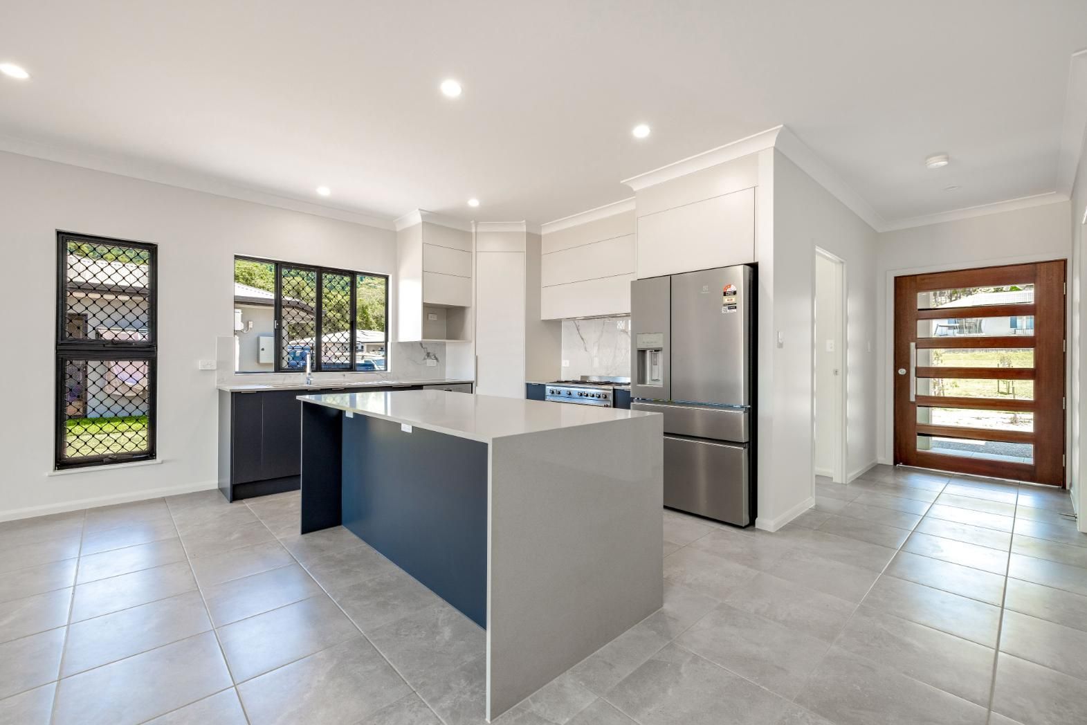 A Kitchen With a Large Island and Stainless Steel Appliances — Ashlee Jones Homes in Gordonvale, QLD