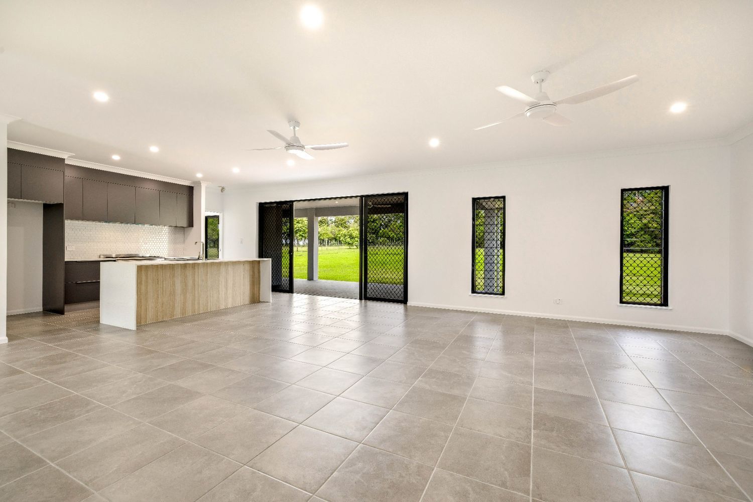 A Large Empty Room With a Tiled Floor and a Ceiling Fan — Ashlee Jones Homes in Gordonvale, QLD