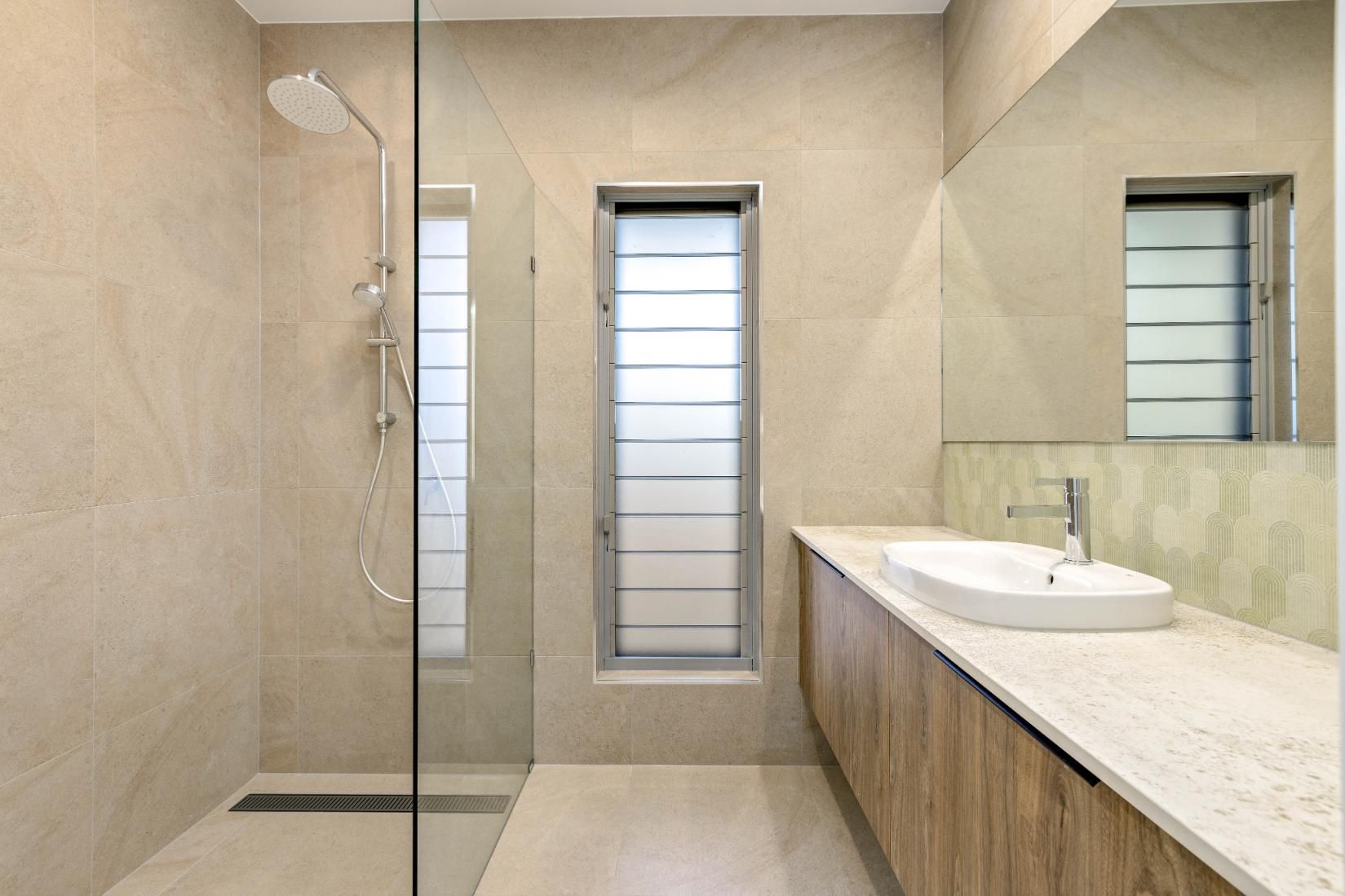 A bathroom with a walk in shower , sink and mirror.