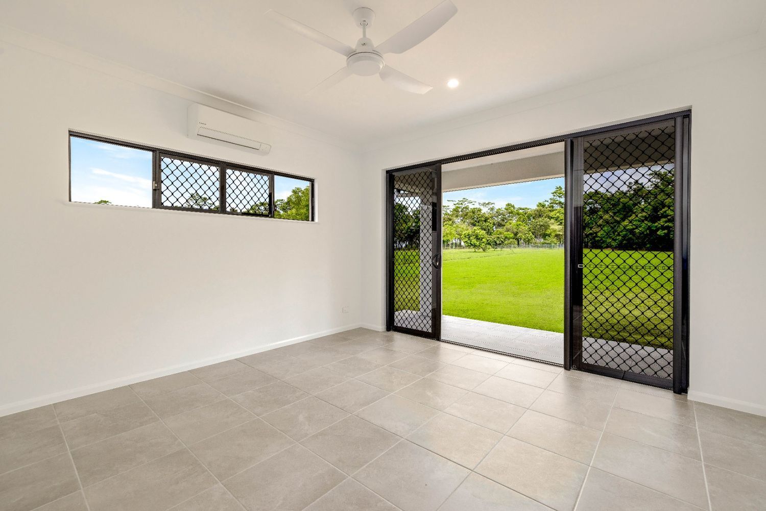 An Empty Room With Sliding Glass Doors and a Ceiling Fan — Ashlee Jones Homes in Gordonvale, QLD