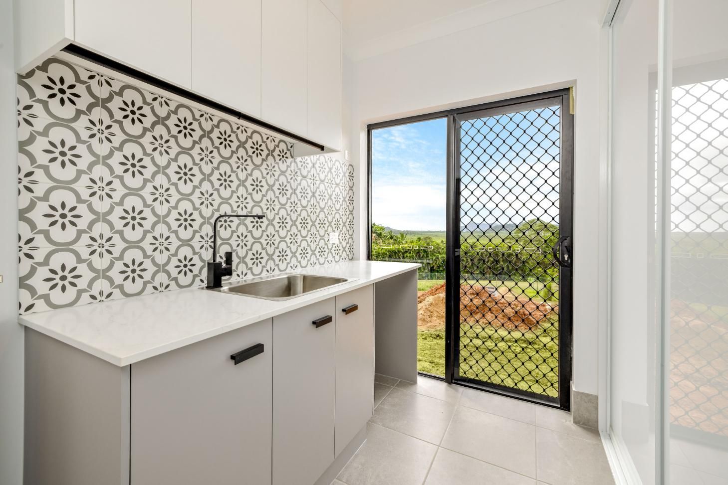 A Kitchen With a Sink, Cabinets, and a Sliding Glass Door — Ashlee Jones Homes in Gordonvale, QLD