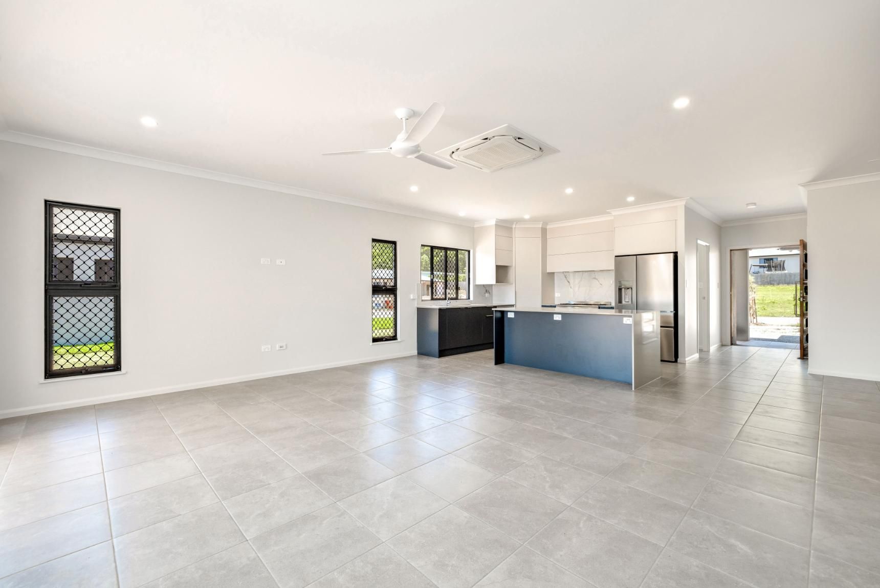 A Large Empty Room With a Kitchen and a Ceiling Fan — Ashlee Jones Homes in Gordonvale, QLD