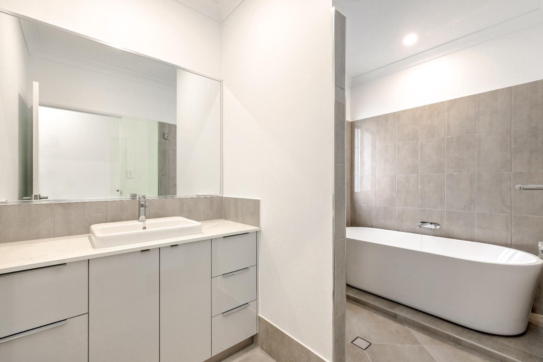 A Bathroom With a Sink, Mirror and Bathtub — Ashlee Jones Homes in Gordonvale, QLD
