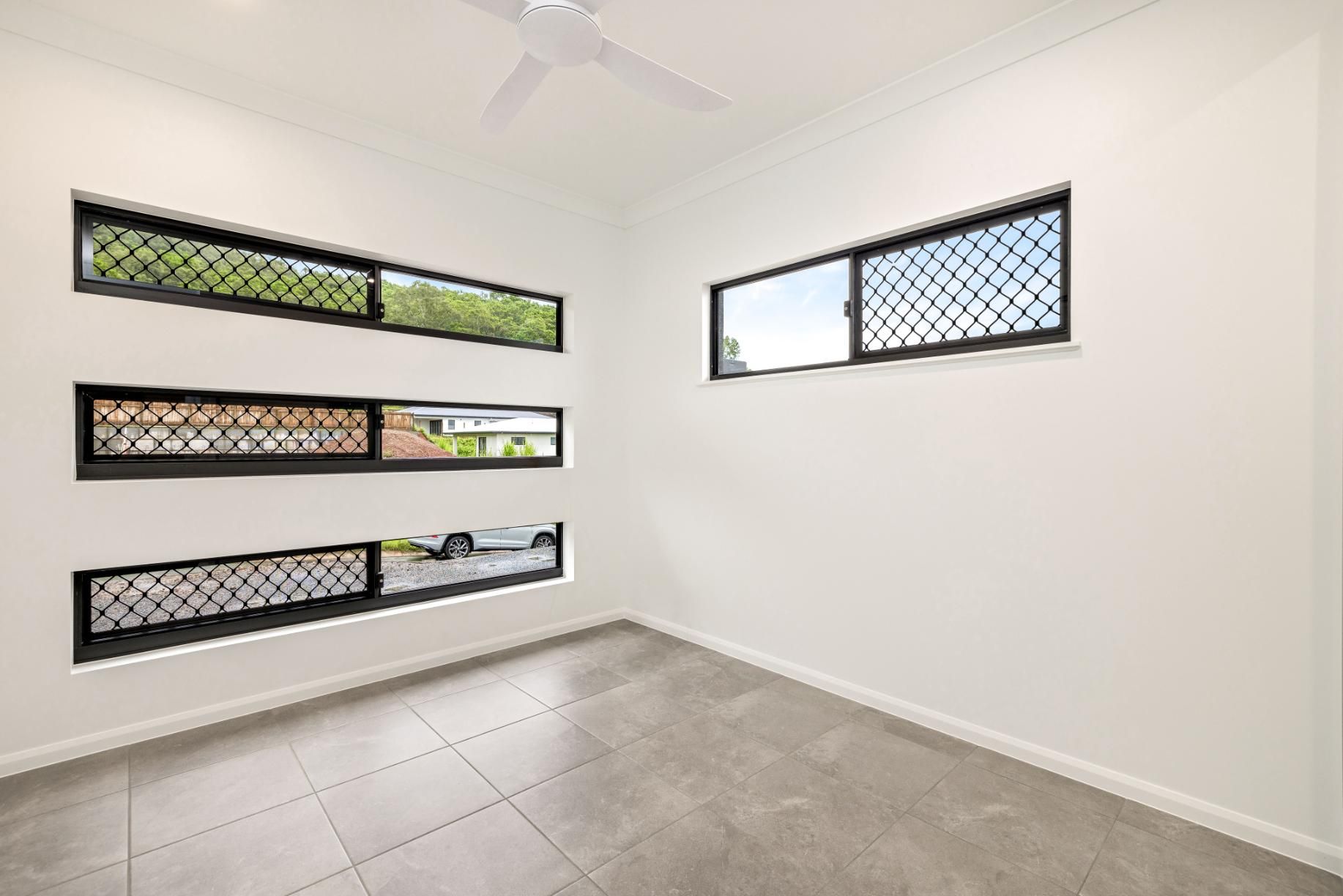 An Empty Room With Three Windows and a Ceiling Fan — Ashlee Jones Homes in Gordonvale, QLD