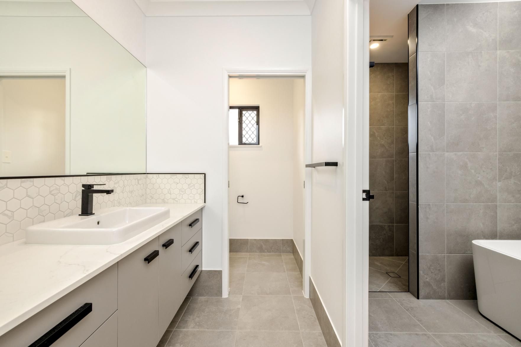 A Bathroom With a Sink, Mirror and Tub — Ashlee Jones Homes in Gordonvale, QLD