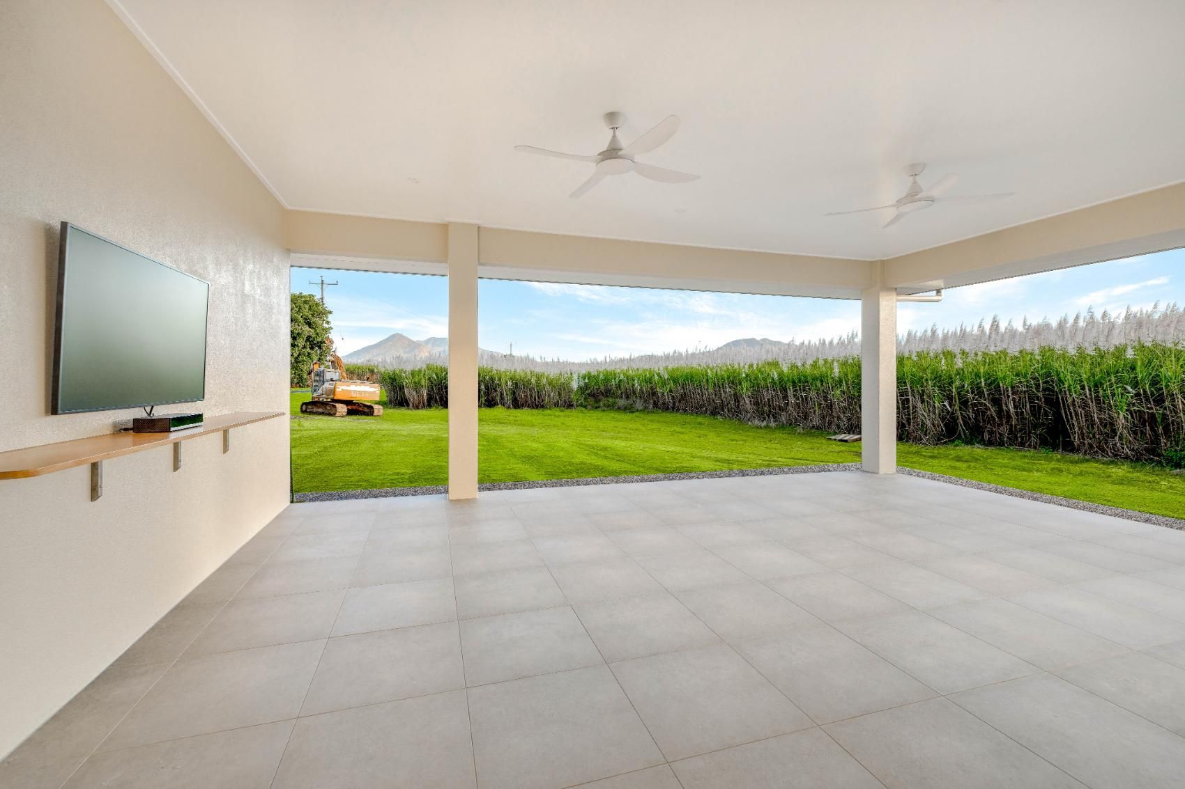 An Empty Room With a Television on the Wall and a Ceiling Fan — Ashlee Jones Homes in Gordonvale, QLD
