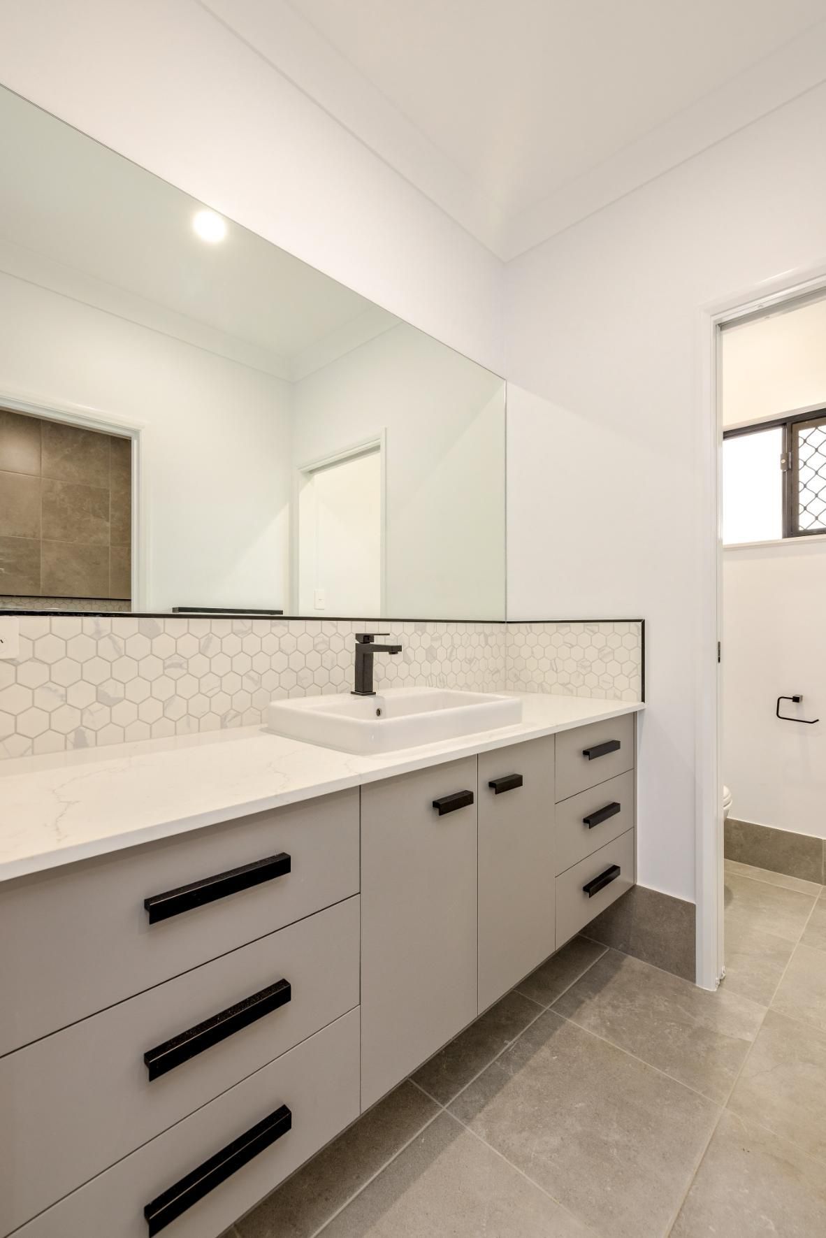 A Bathroom With a Sink, Mirror and Drawers — Ashlee Jones Homes in Gordonvale, QLD