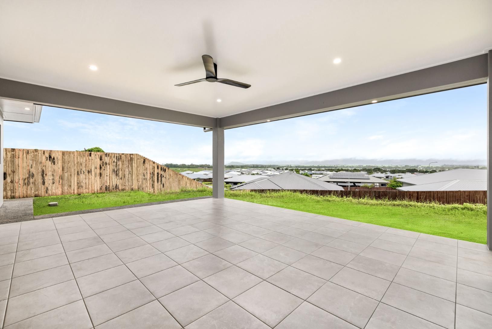 An Empty Patio With a Ceiling Fan and a View of a Grassy Field — Ashlee Jones Homes in Gordonvale, QLD