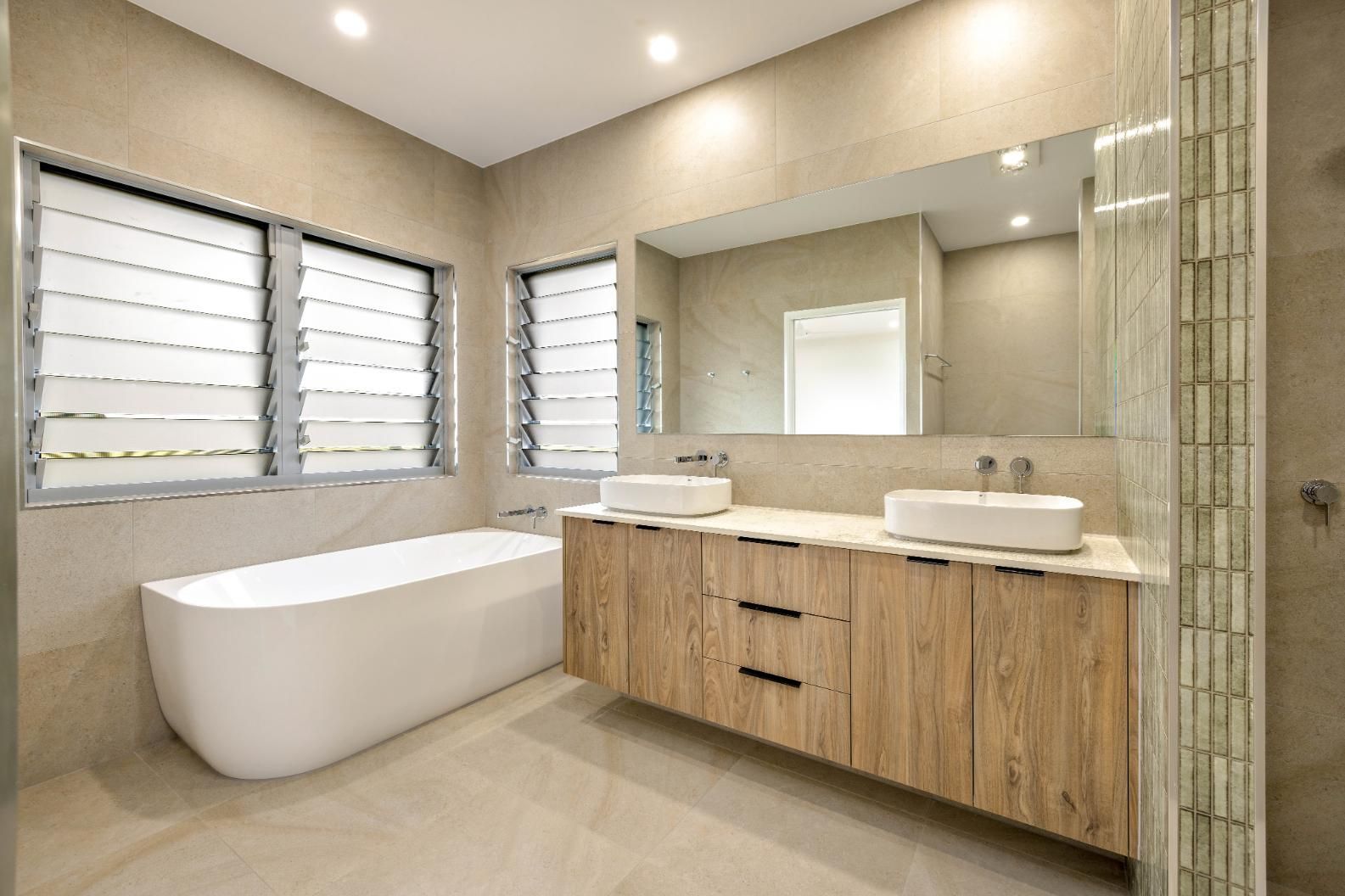 A Bathroom With Two Sinks, a Bathtub and a Large Mirror — Ashlee Jones Homes in Gordonvale, QLD
