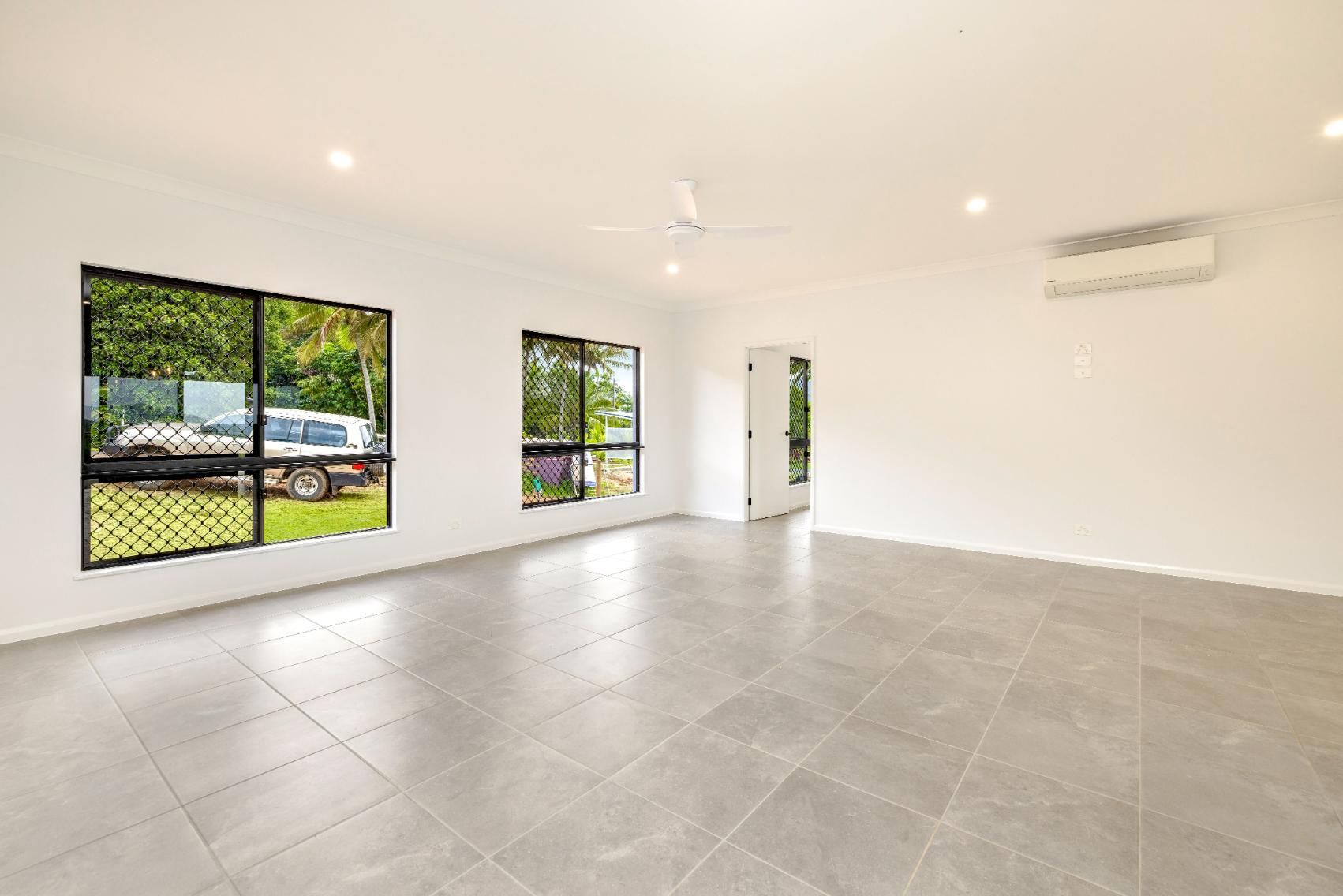 An Empty Living Room With Tile Floors and a Ceiling Fan — Ashlee Jones Homes in Gordonvale, QLD