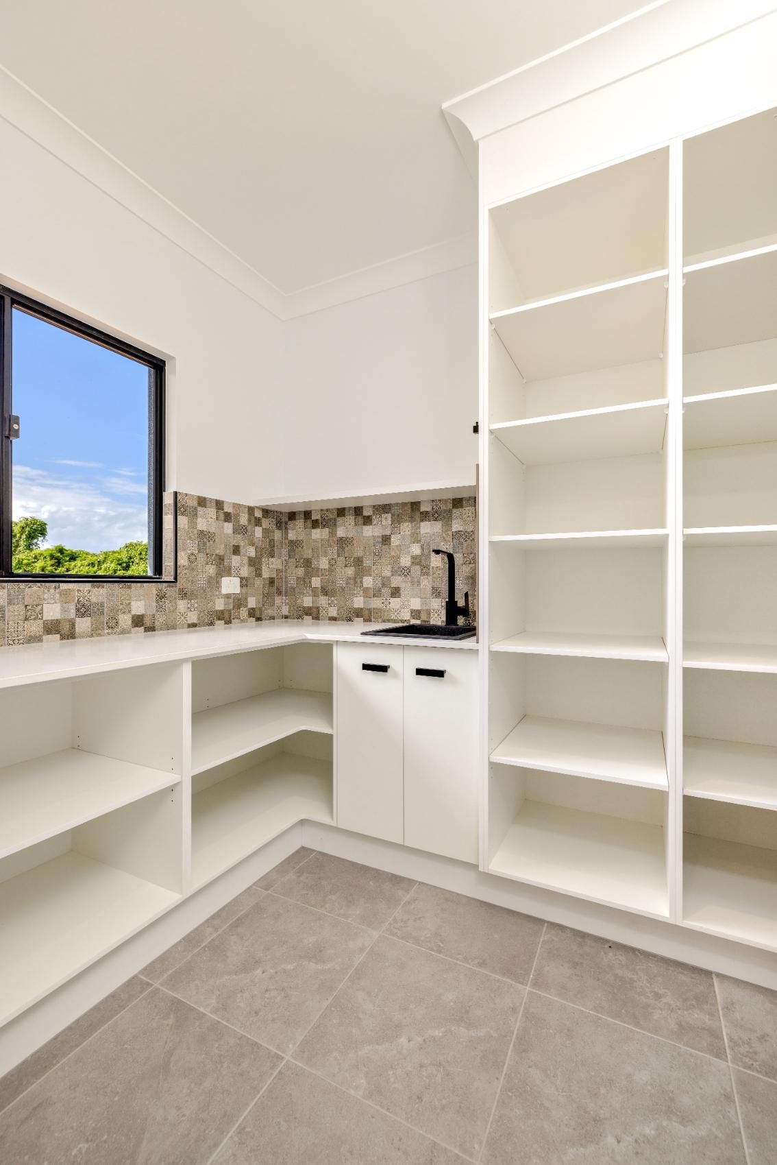 A Kitchen With White Cabinets and Shelves and a Window — Ashlee Jones Homes in Gordonvale, QLD