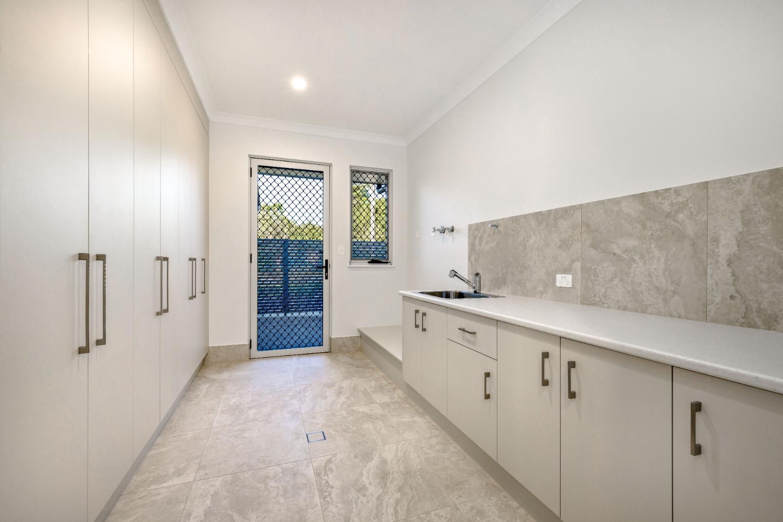 An Empty Kitchen With White Cabinets and a Sink — Ashlee Jones Homes in Gordonvale, QLD