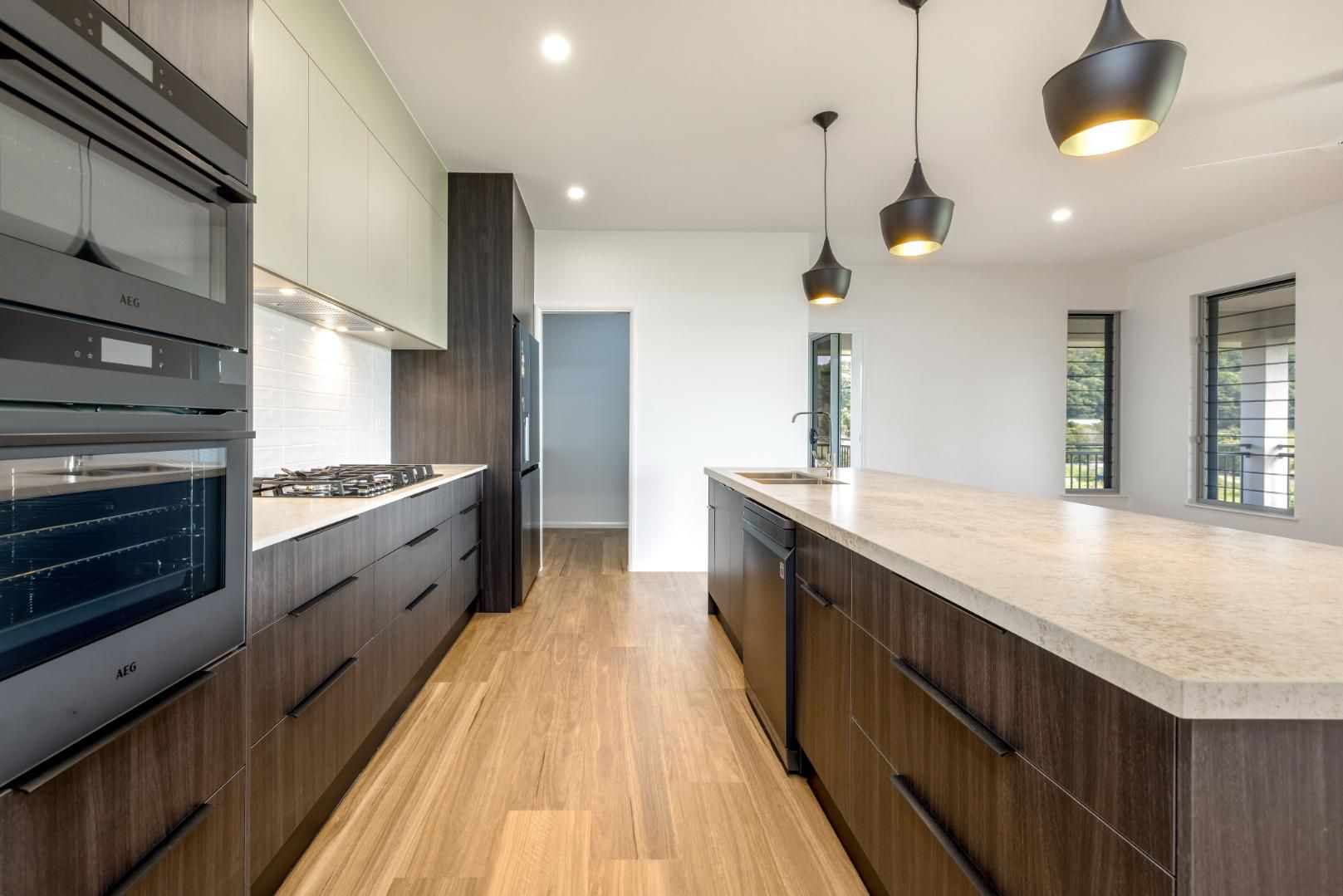 A Kitchen With Wooden Cabinets, Granite Countertops, and Stainless Steel Appliances — Ashlee Jones Homes in Gordonvale, QLD