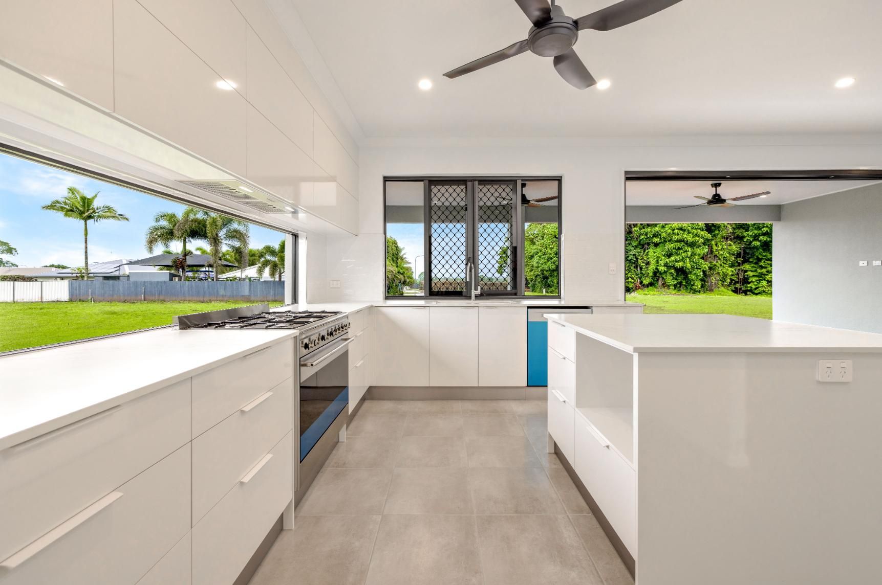a Kitchen With White Cabinets, Stainless Steel Appliances, and a Ceiling Fan — Ashlee Jones Homes in Gordonvale, QLD