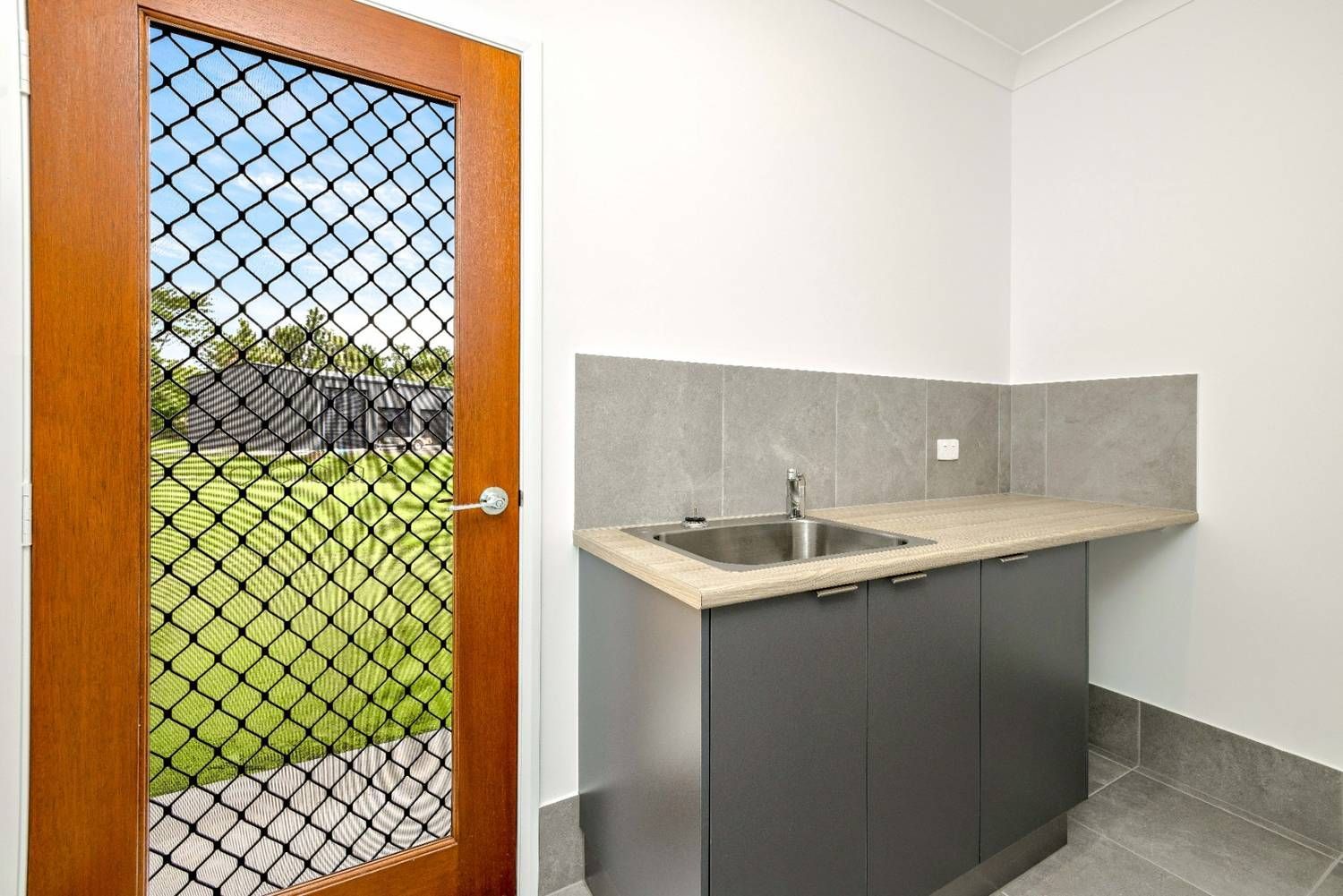 A Kitchen With a Sink, Cabinets, and a Fenced in Door — Ashlee Jones Homes in Gordonvale, QLD