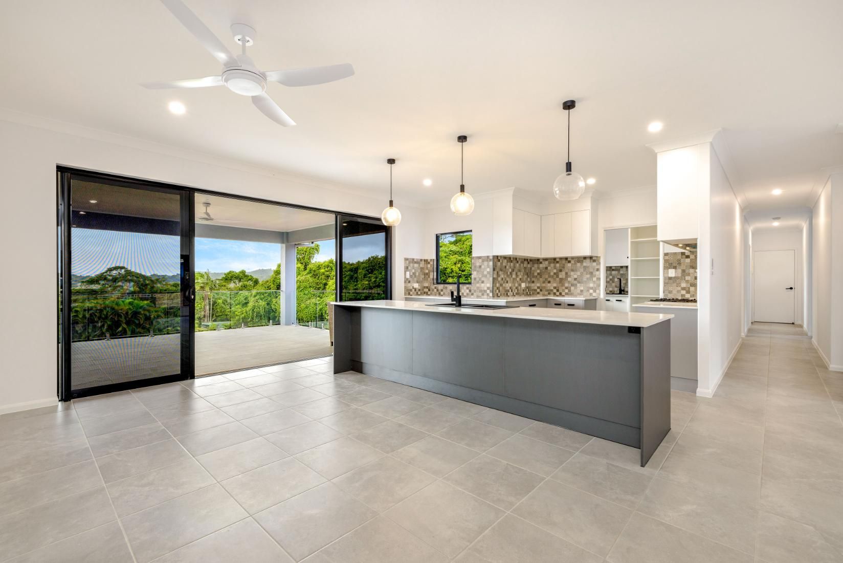An Empty Kitchen With a Large Island and a Ceiling Fan — Ashlee Jones Homes in Gordonvale, QLD